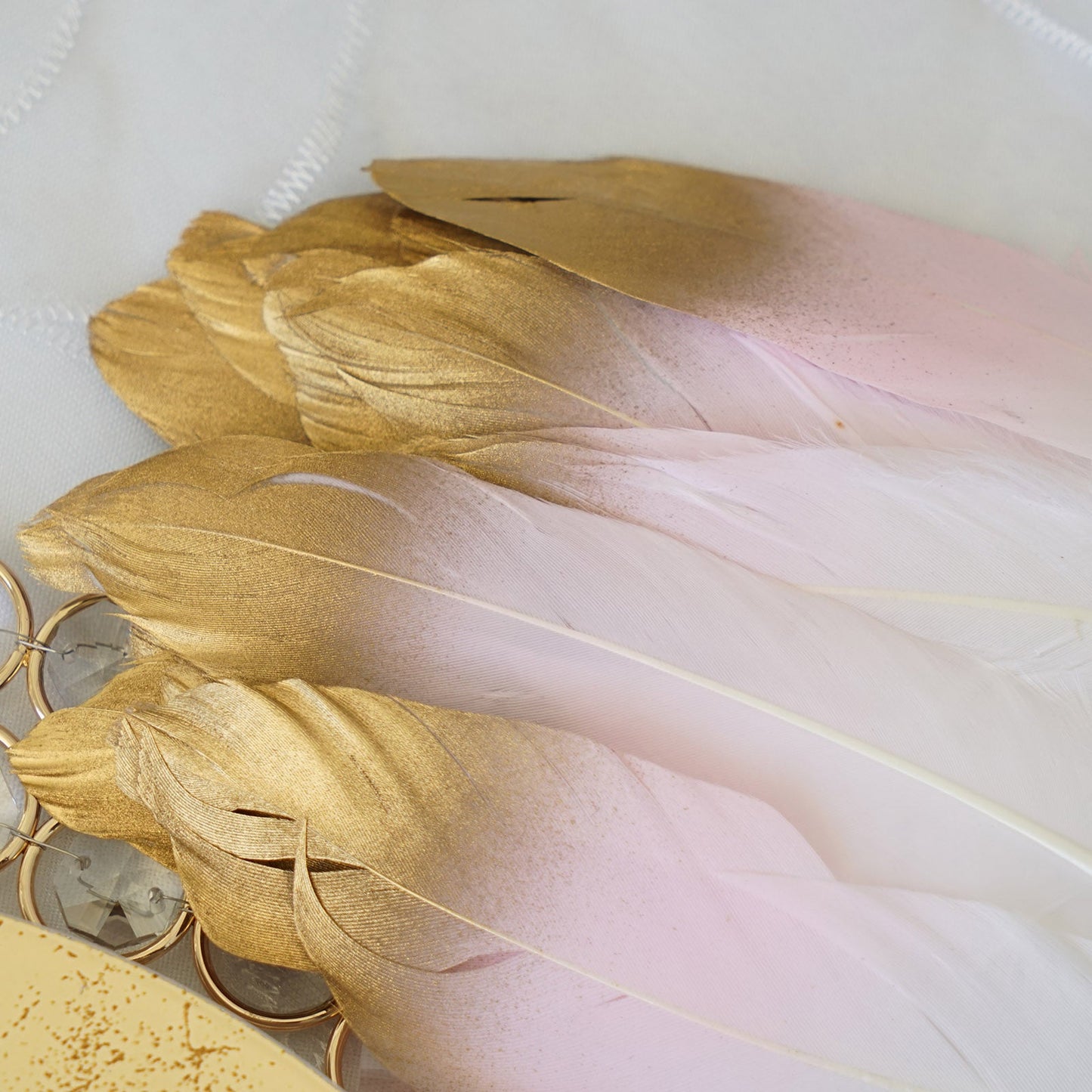 Metallic gold tip dual tone blush white craft feathers for party decoration.