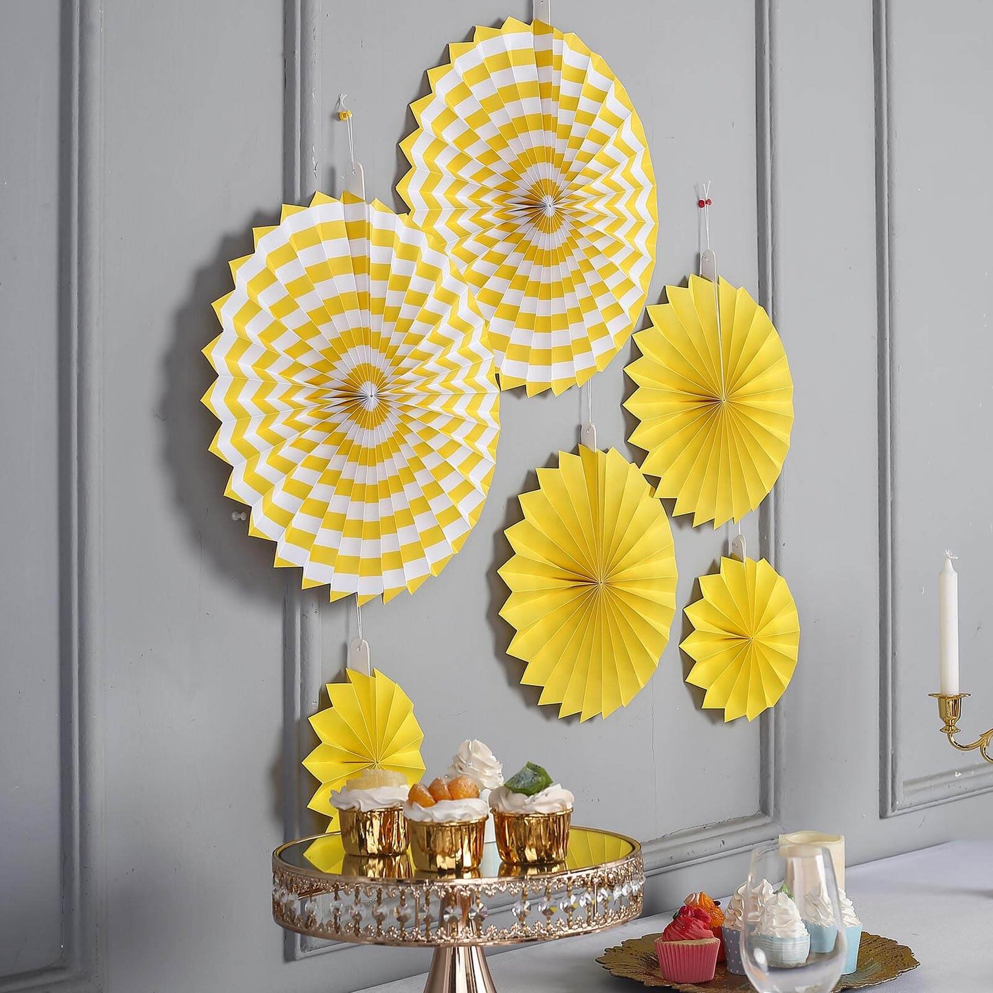 Yellow hanging paper fan decorations set, perfect for party backdrops.