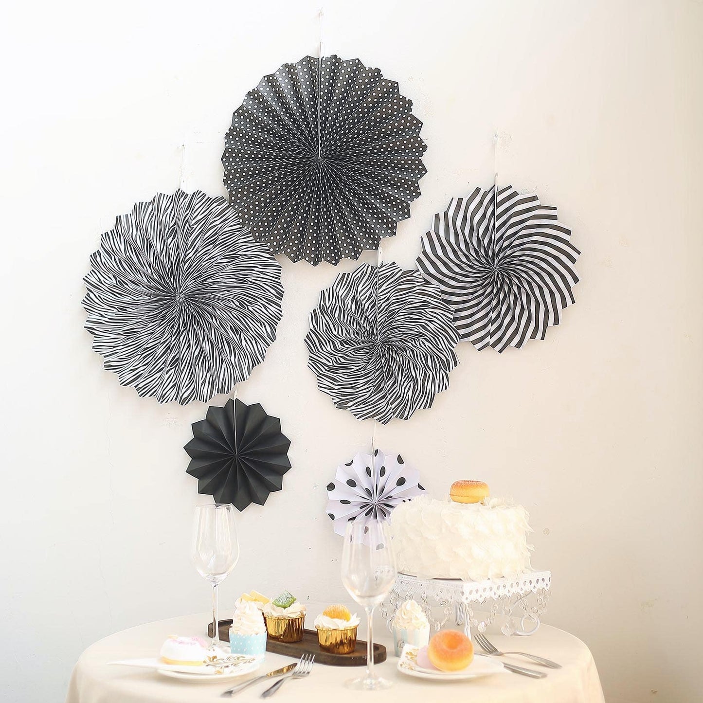 Black and white hanging paper fan decorations set on a wall backdrop.