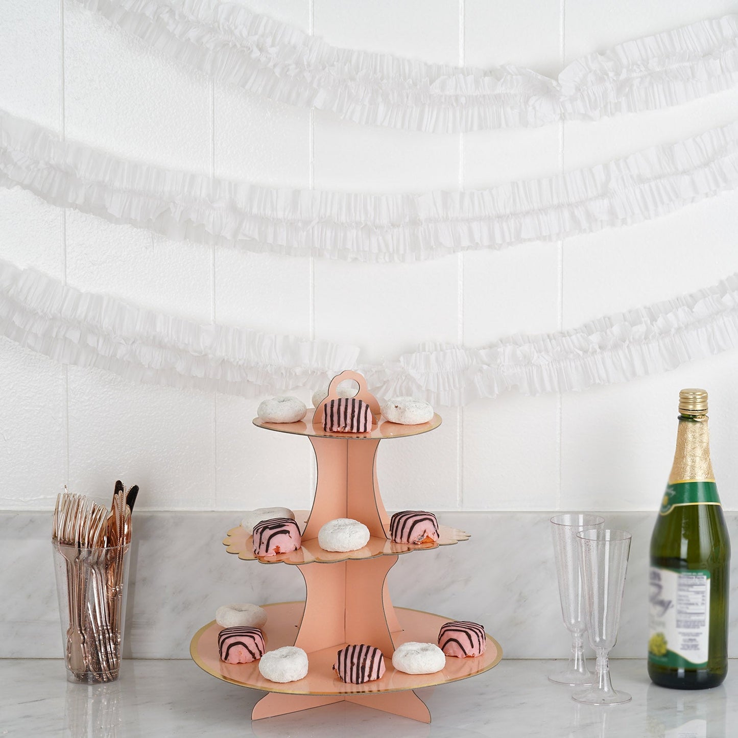 White ruffled paper streamers and pastel treats on a decorative stand.