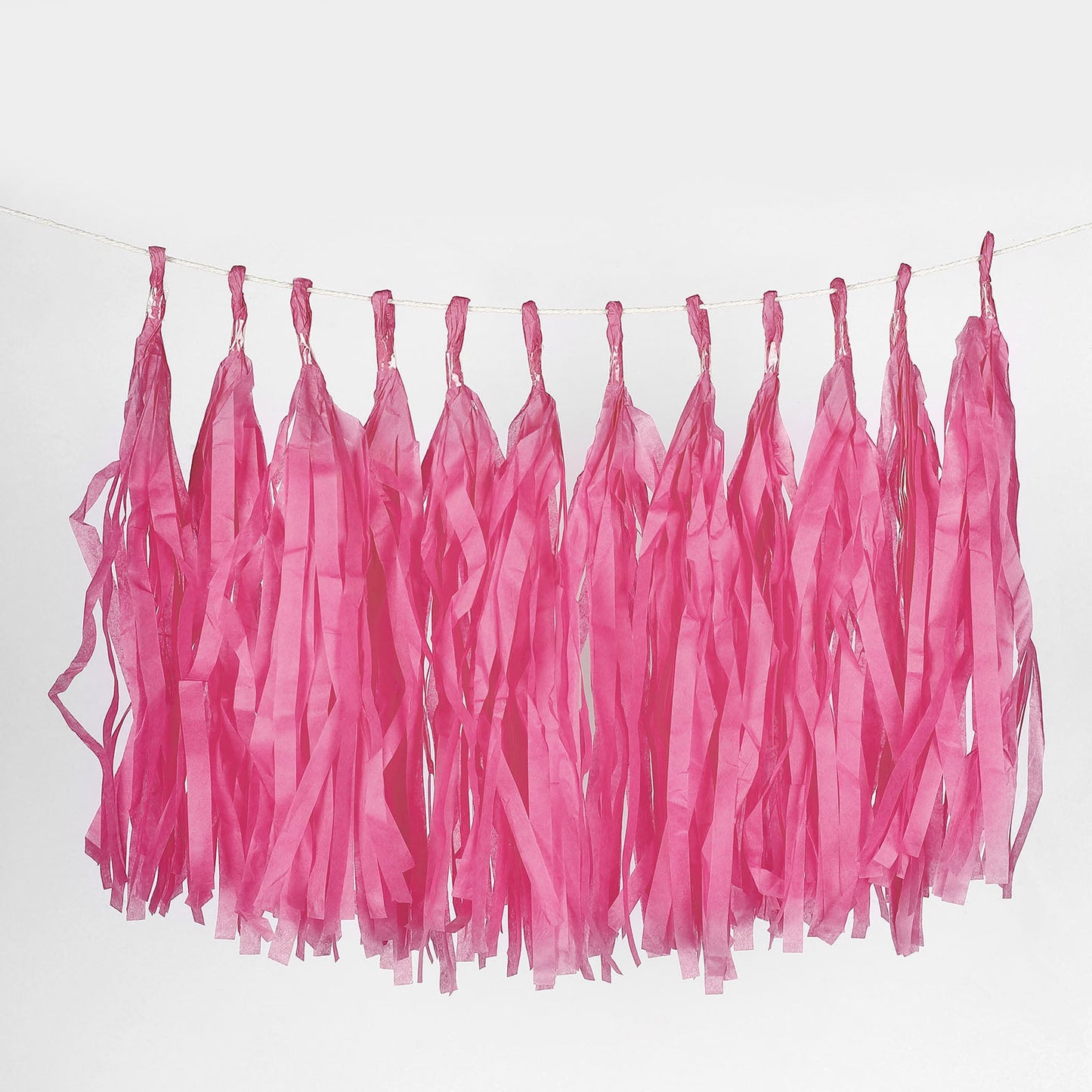 Fuchsia paper fringe tassels hanging on a garland string.