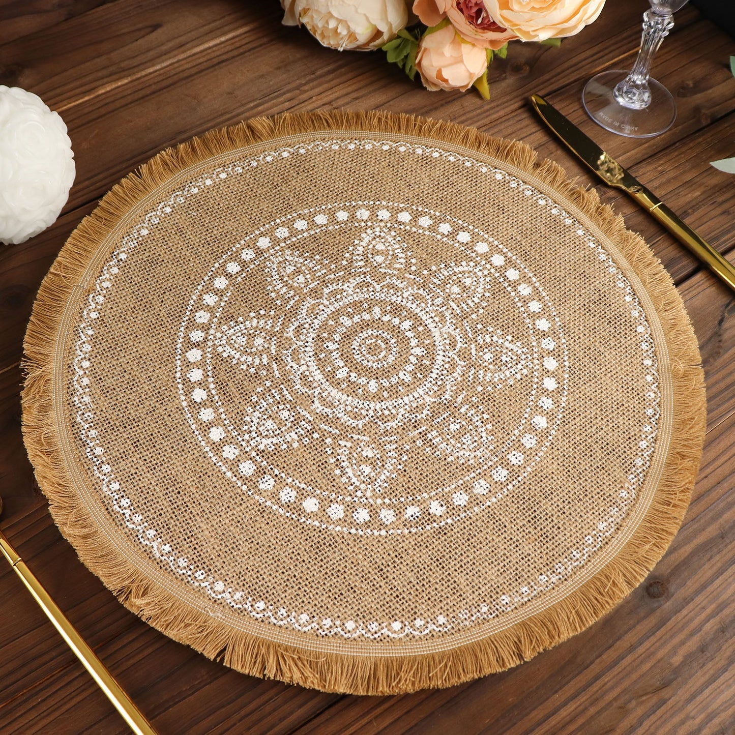 Natural jute round placemat with white embroidery and fringe details.