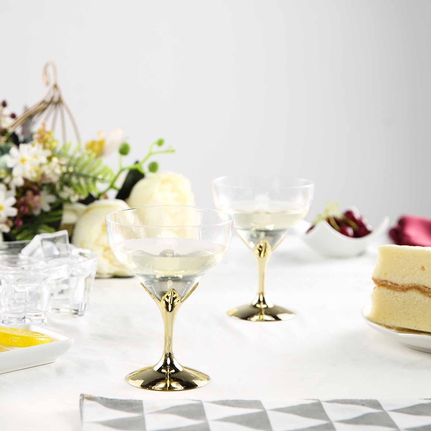 Gold disposable champagne glasses with detachable cups on a table setting.