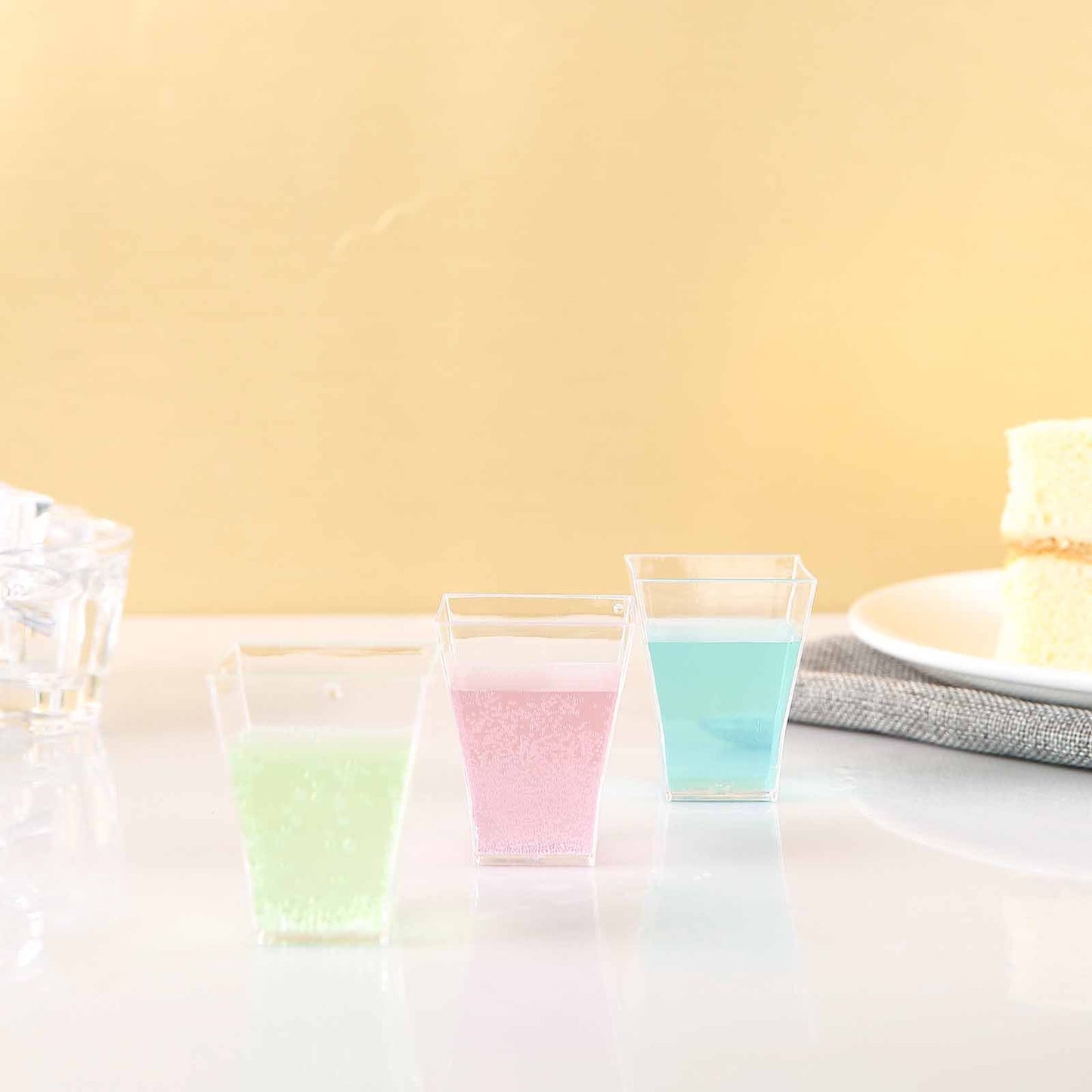 Clear 2oz square plastic shot glasses in pastel colors.