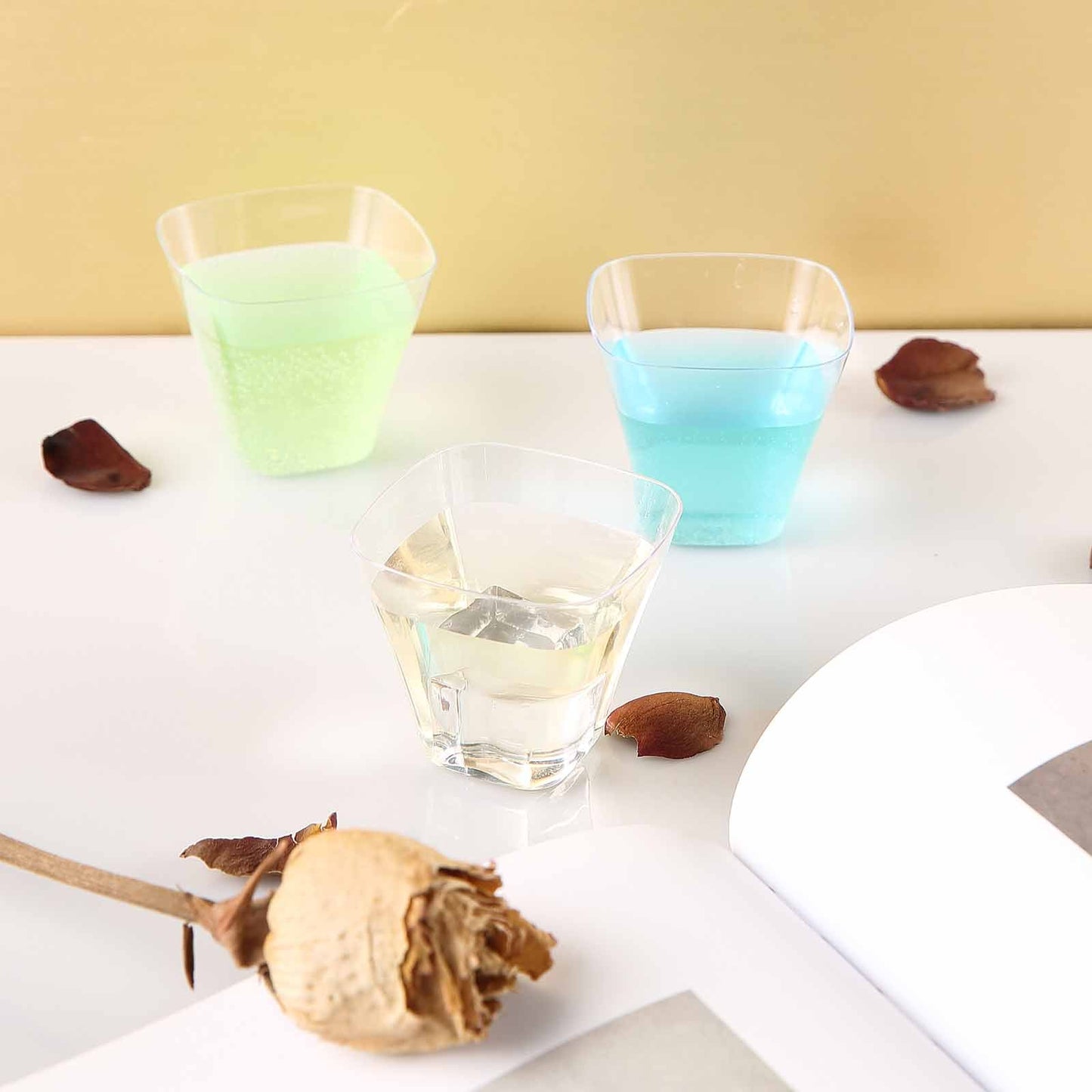 Clear rounded cube plastic cups filled with colorful liquids.