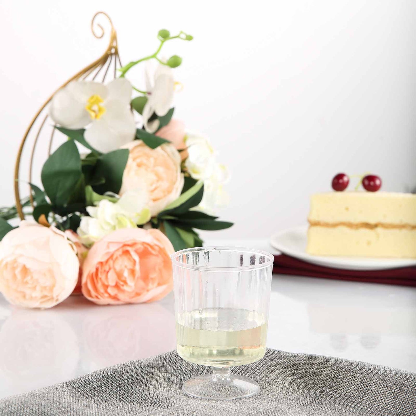Clear short stem disposable plastic wine glasses with white wine.