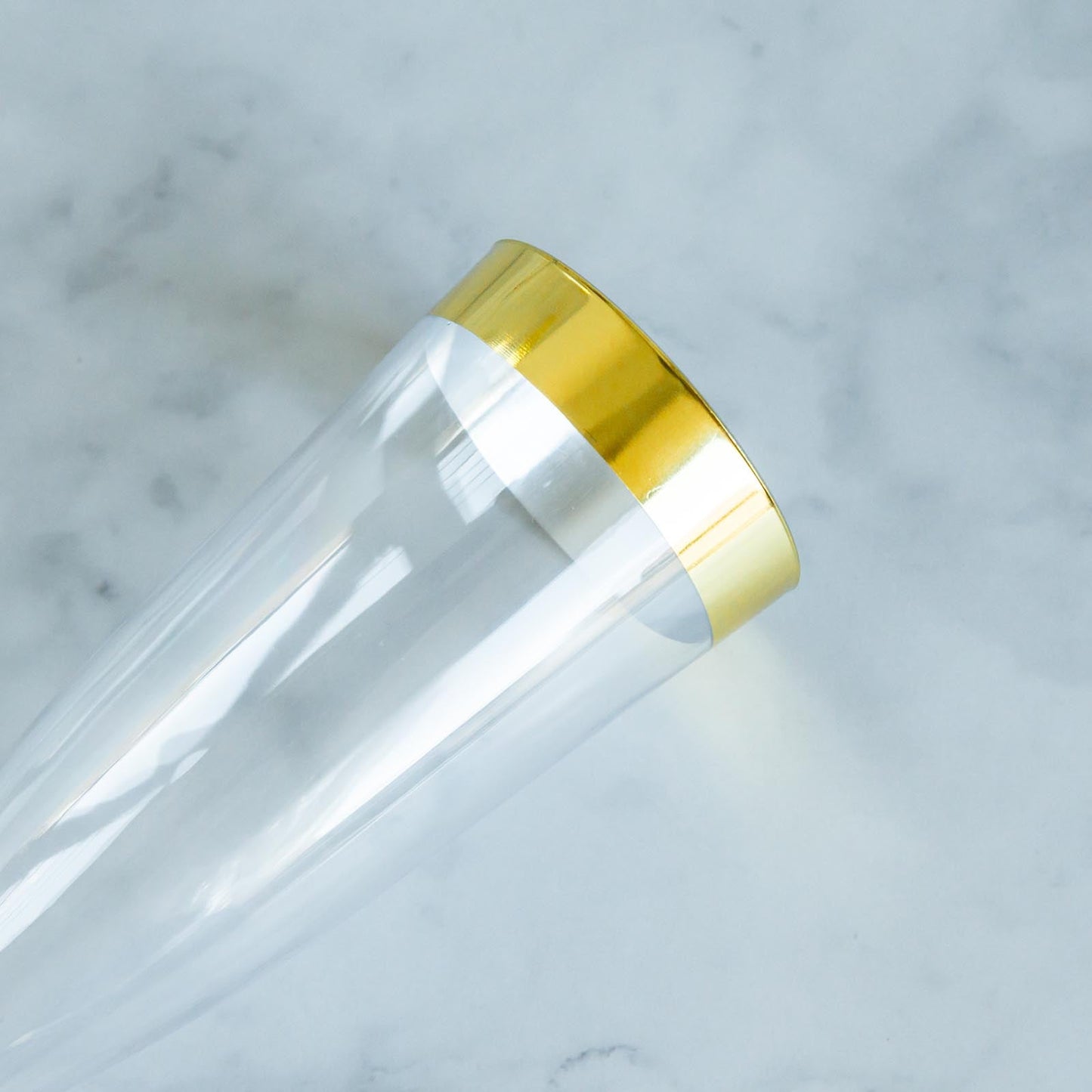 Clear and gold disposable champagne flute with detachable base.