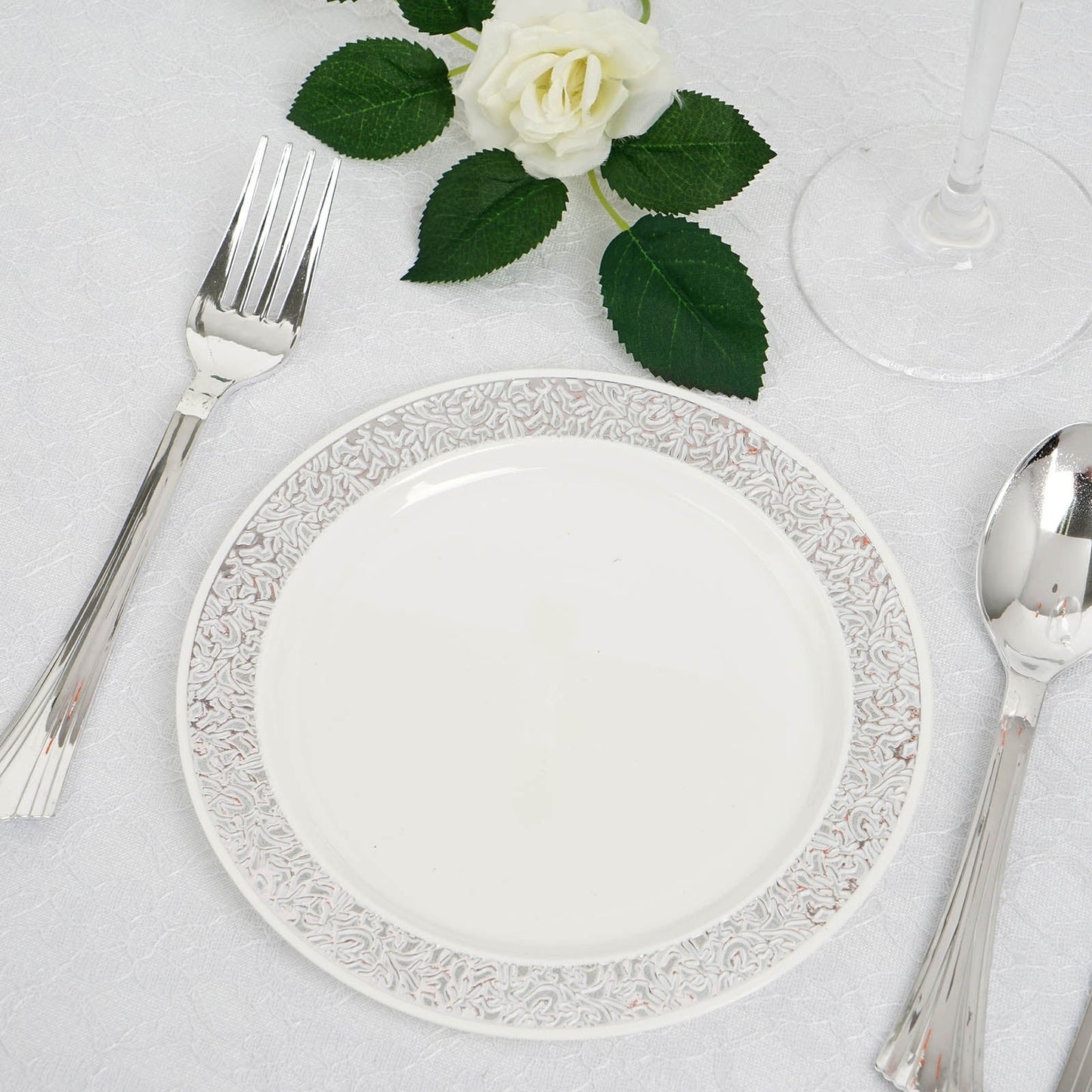 Silver lace rim white plastic dessert appetizer plate on a table setting.