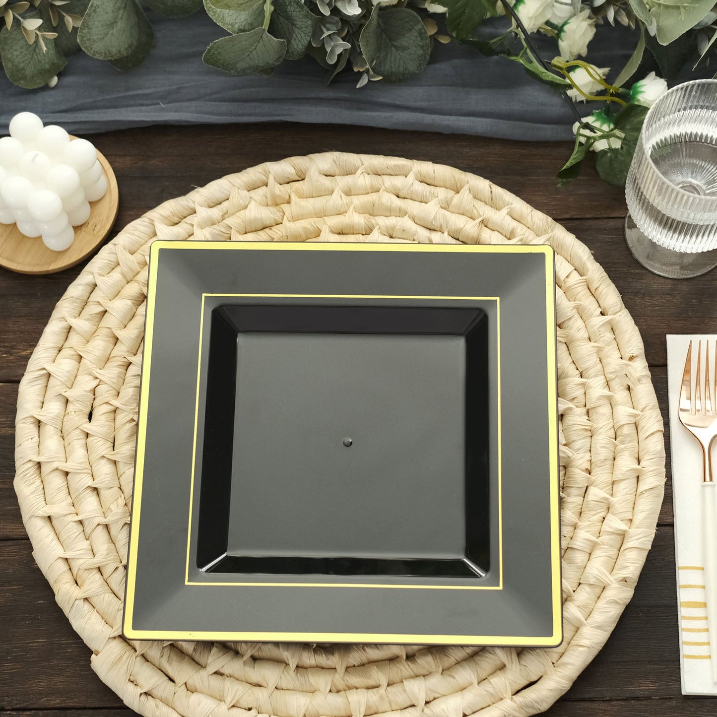 Gold trim black square disposable dinner plate on a woven placemat.