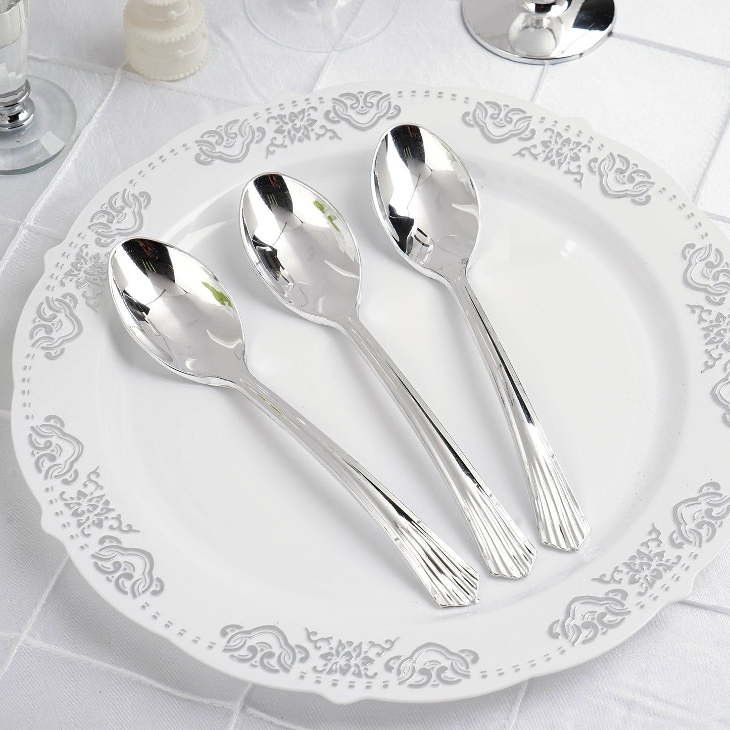 Silver heavy duty plastic spoons on a decorative plate.