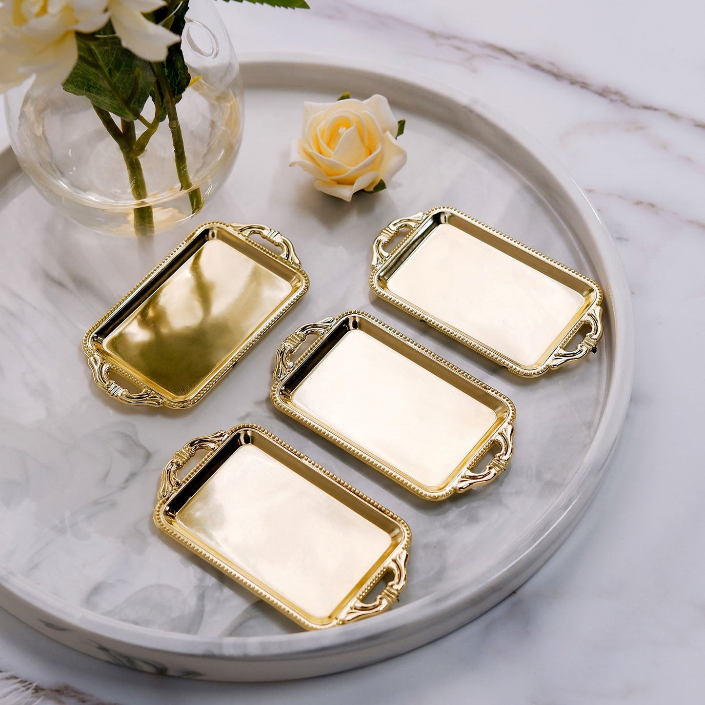 Gold rectangular mini party favor candy trays on a marble surface.