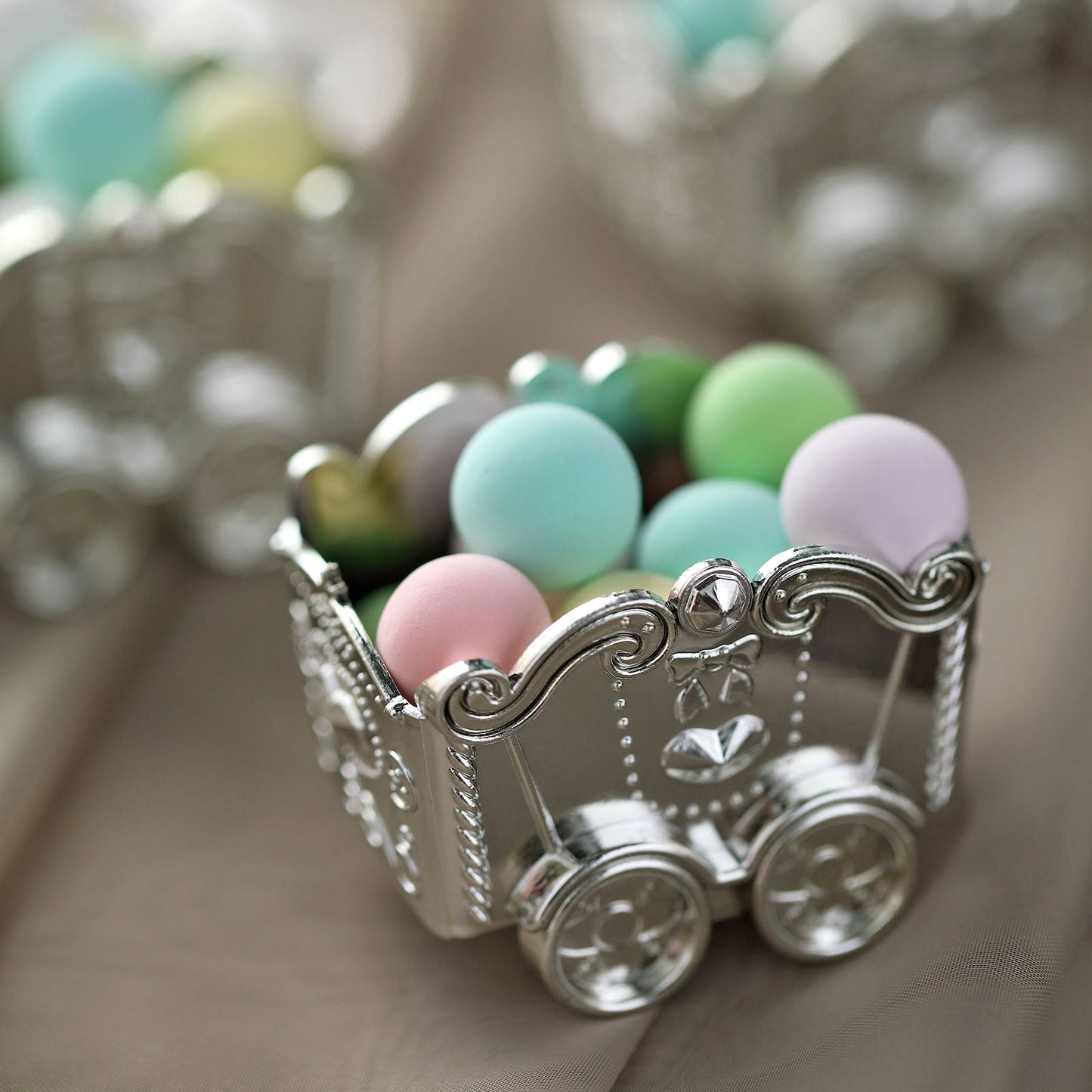Silver chariot party favor gift boxes filled with pastel candies.