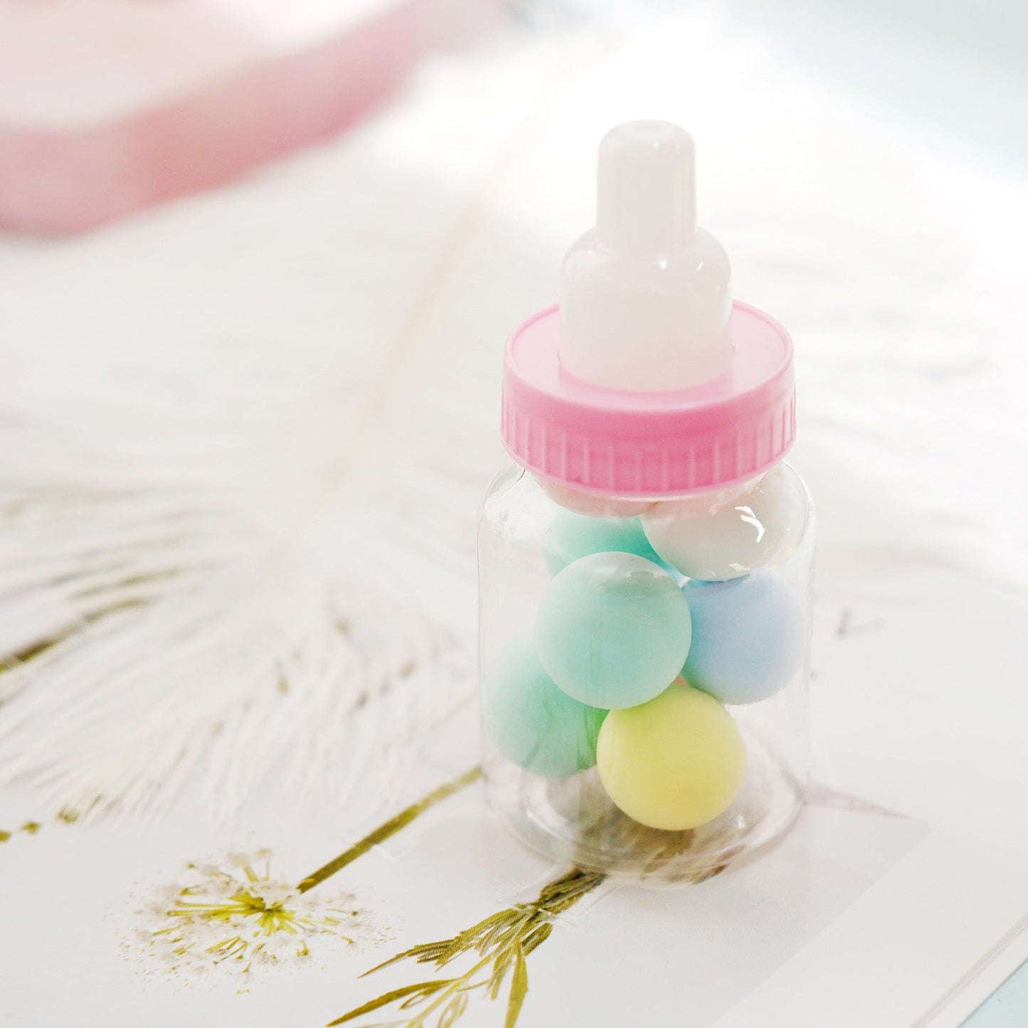 Pink baby bottle candy container with colorful treats inside.