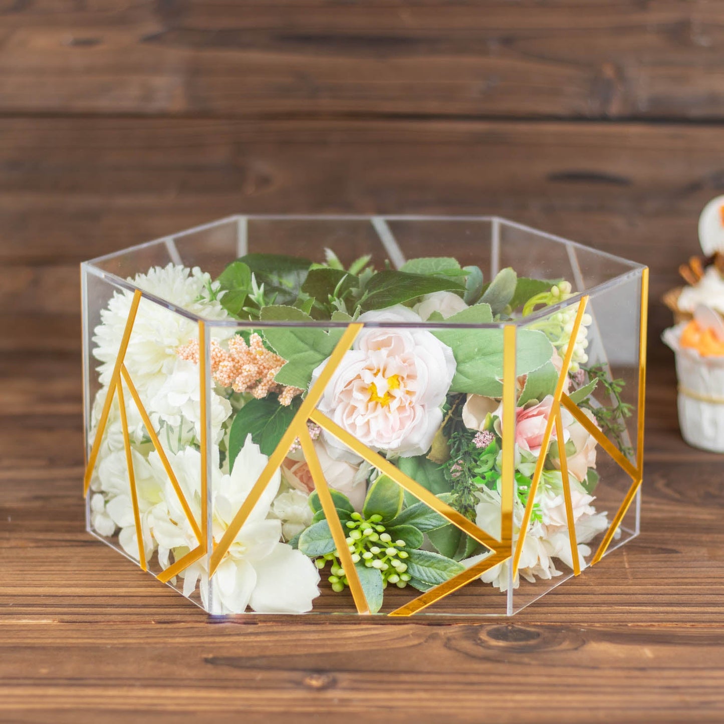 Clear gold hexagonal acrylic cake box stand with flowers inside.