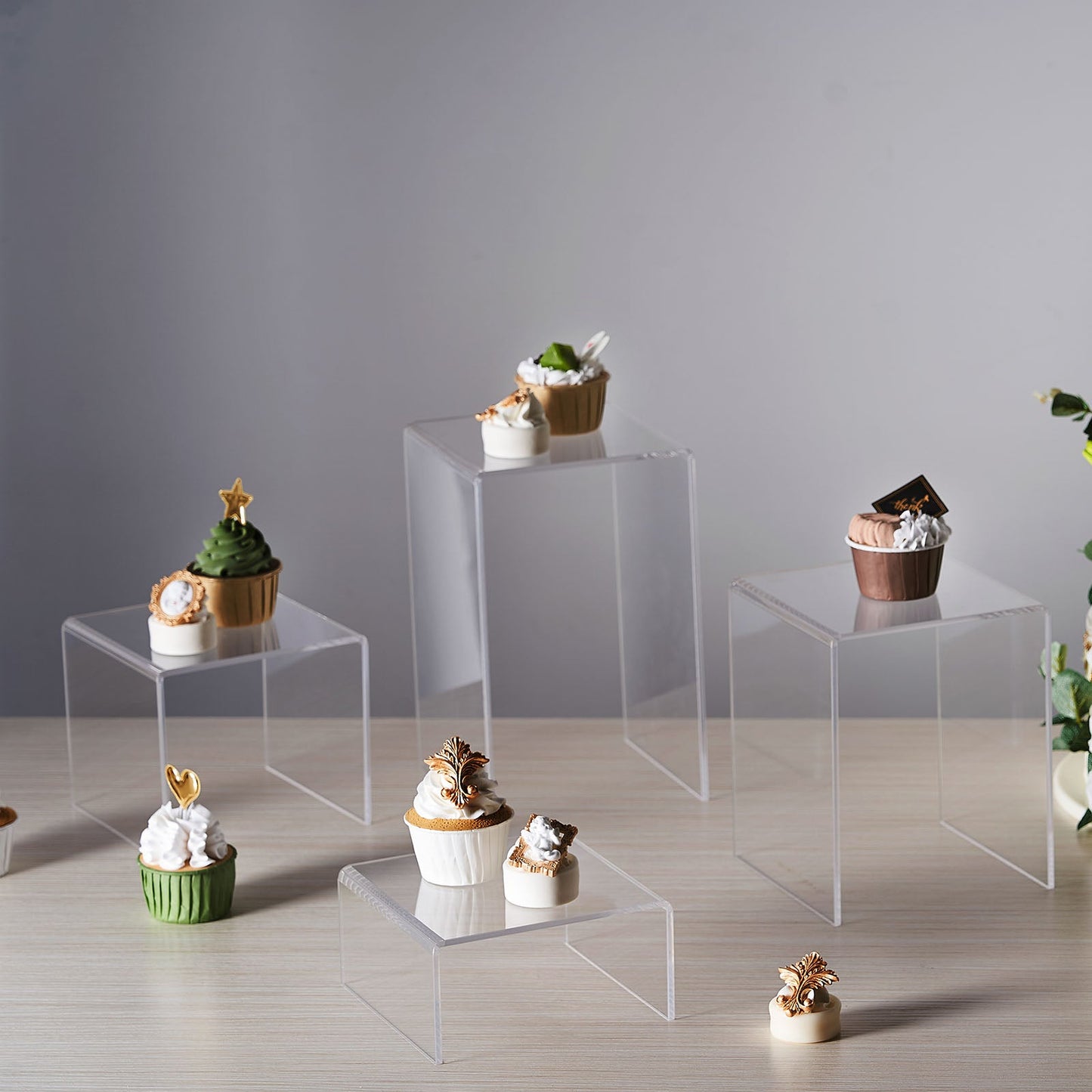 Clear acrylic riser cake stand set displaying assorted cupcakes.