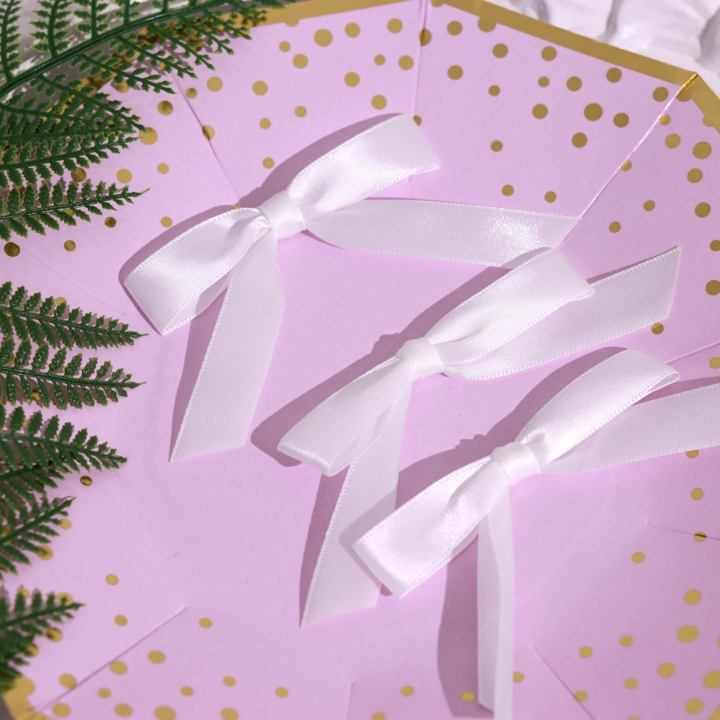 White satin ribbon bows on a decorative plate with gold polka dots.