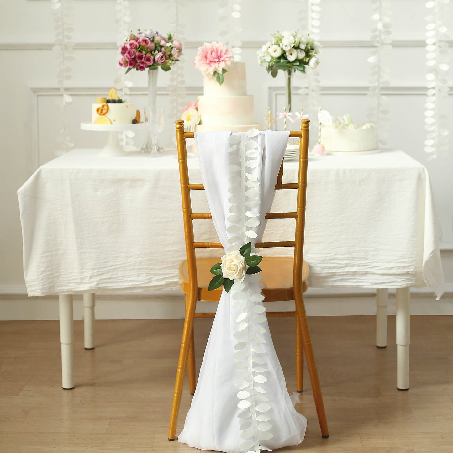 Ivory leaf petal taffeta ribbon sash on a chair at a decorated table.