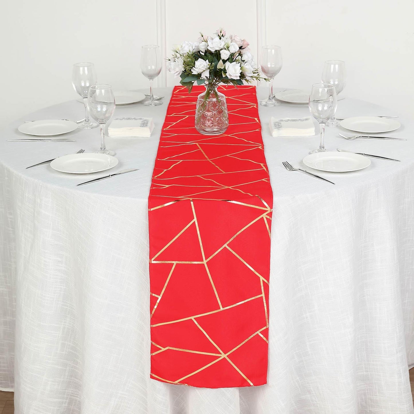 Red table runner with gold foil geometric pattern on a white table.