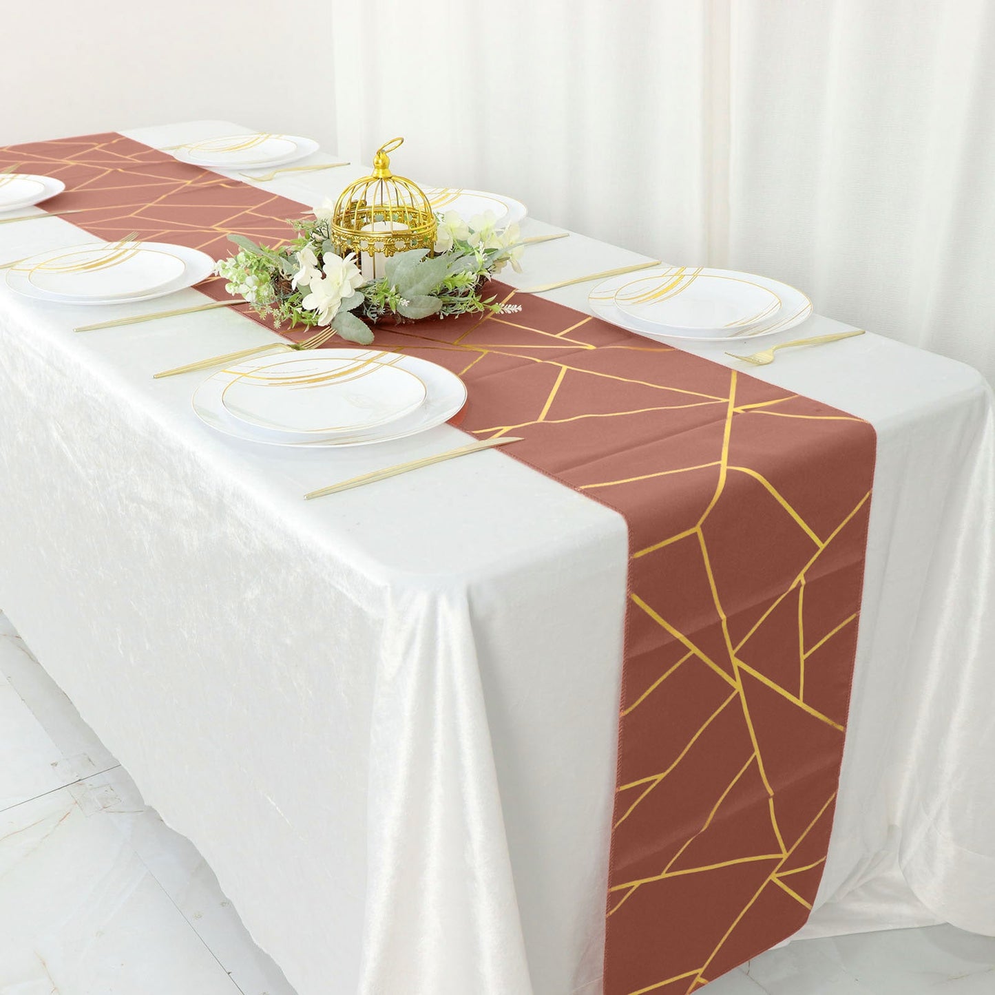 Rust table runner with gold foil geometric pattern on a white table setting.