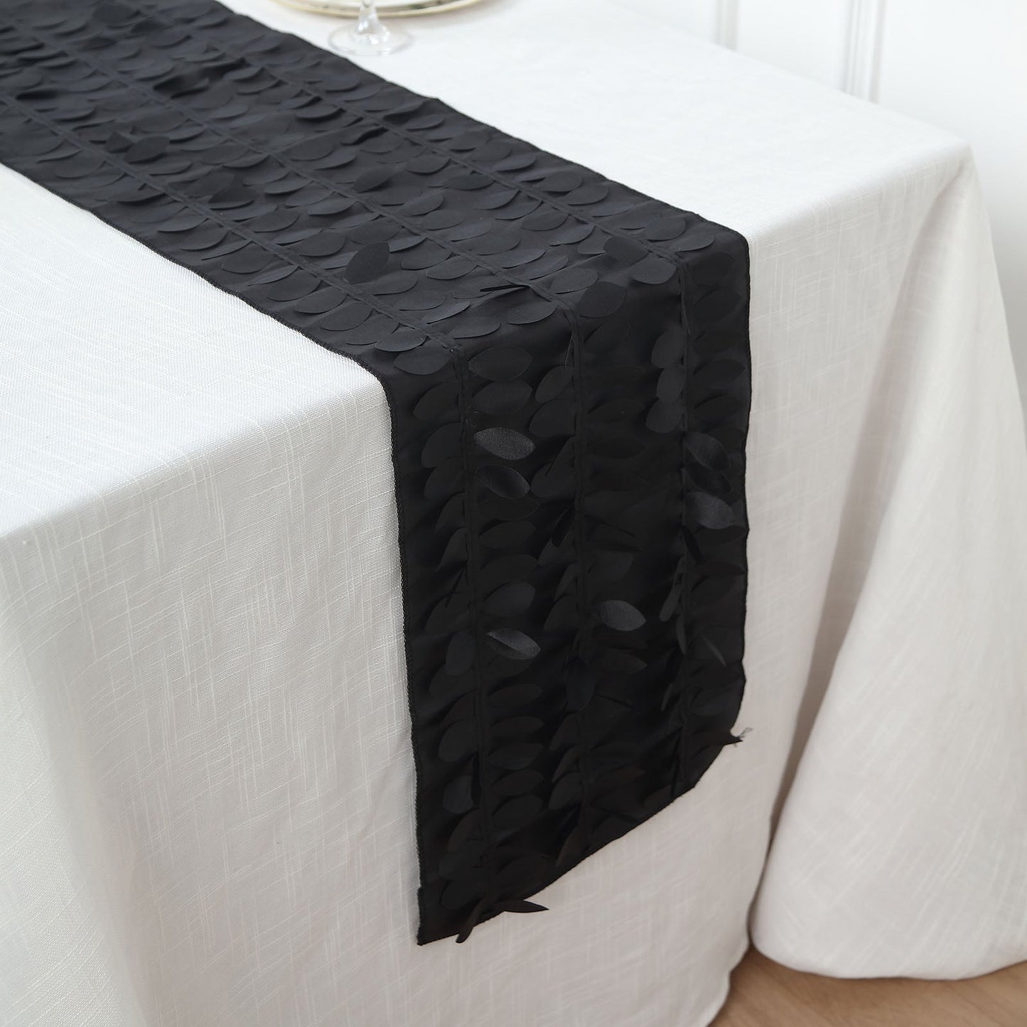 Black 3D leaf petal taffeta fabric table runner on a white table.
