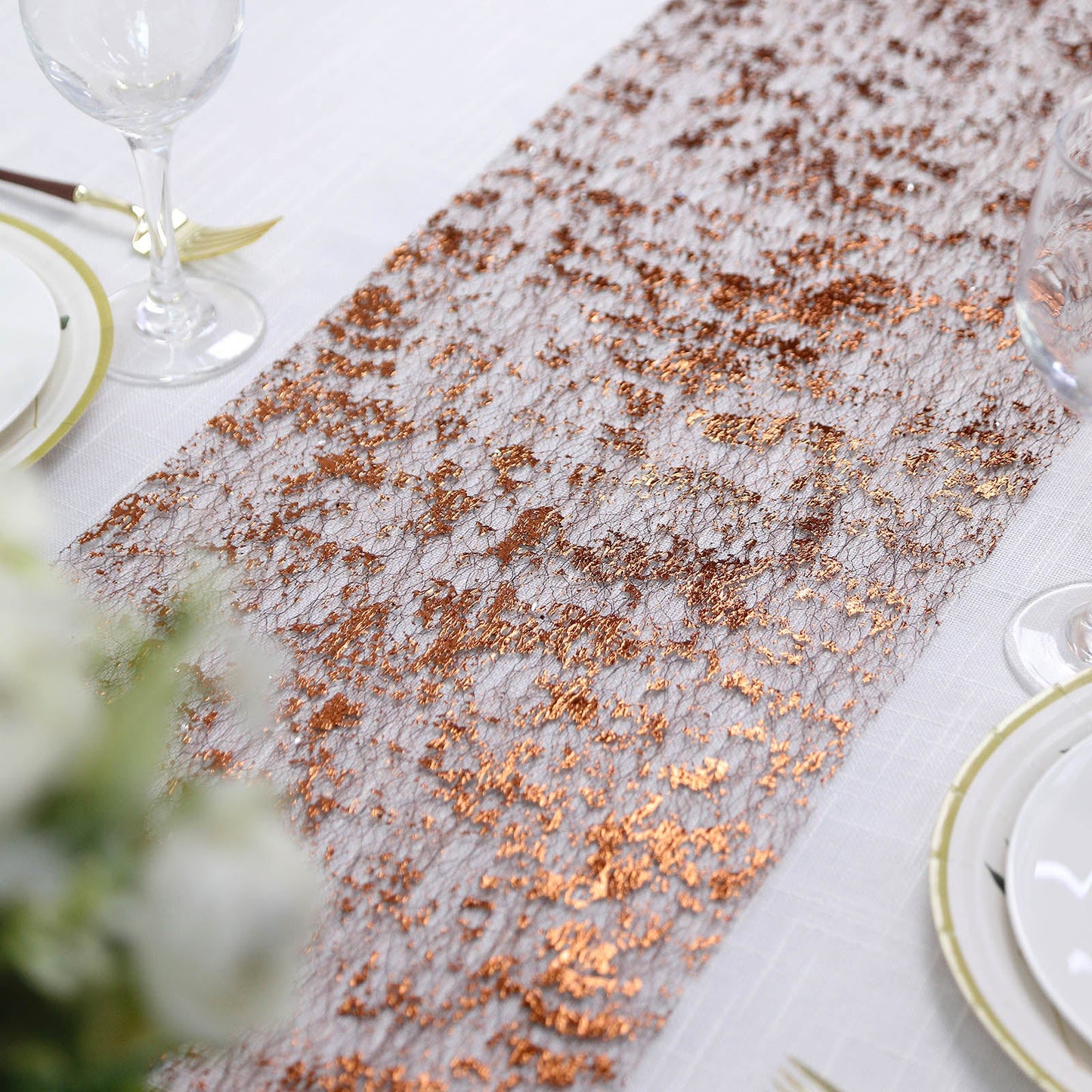 Sparkly metallic bronze foil table runner on a white table setting.