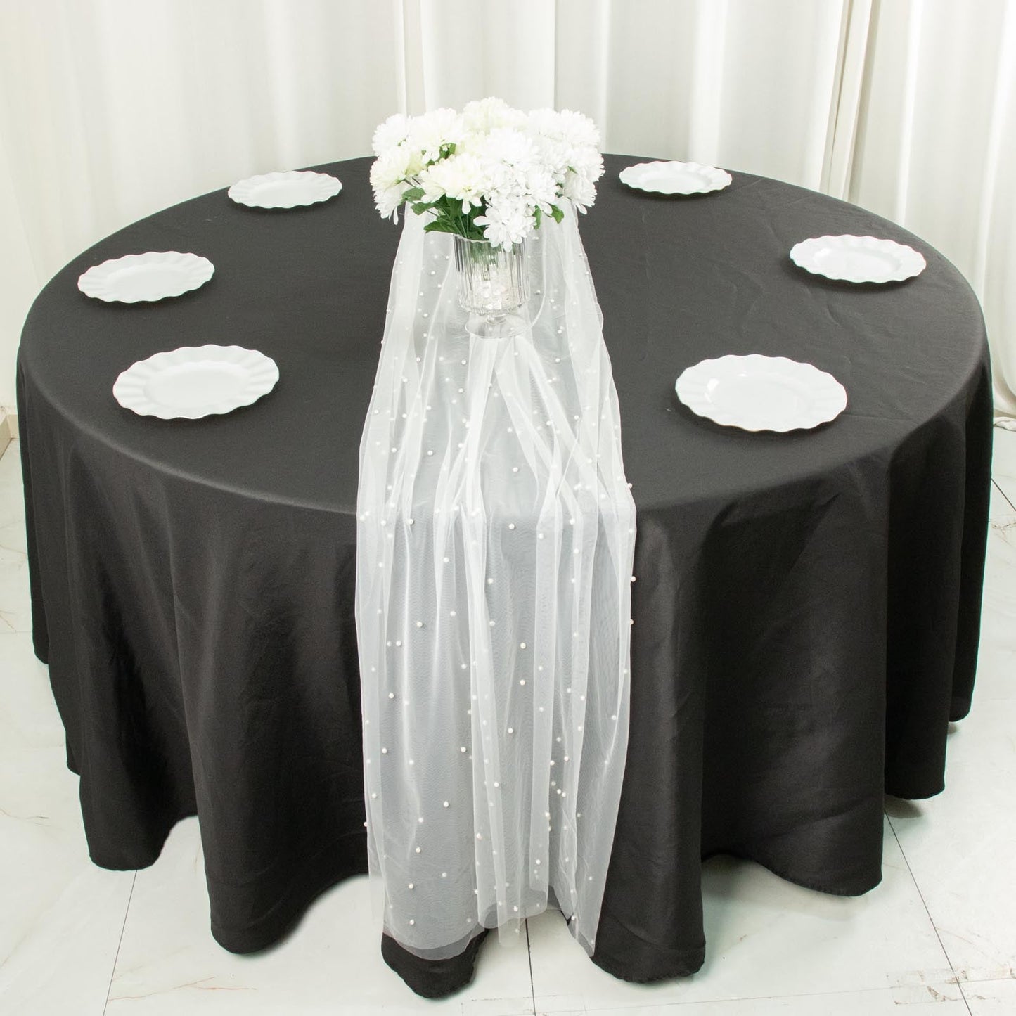 White pearl embellished sheer tulle table runner on a black tablecloth.