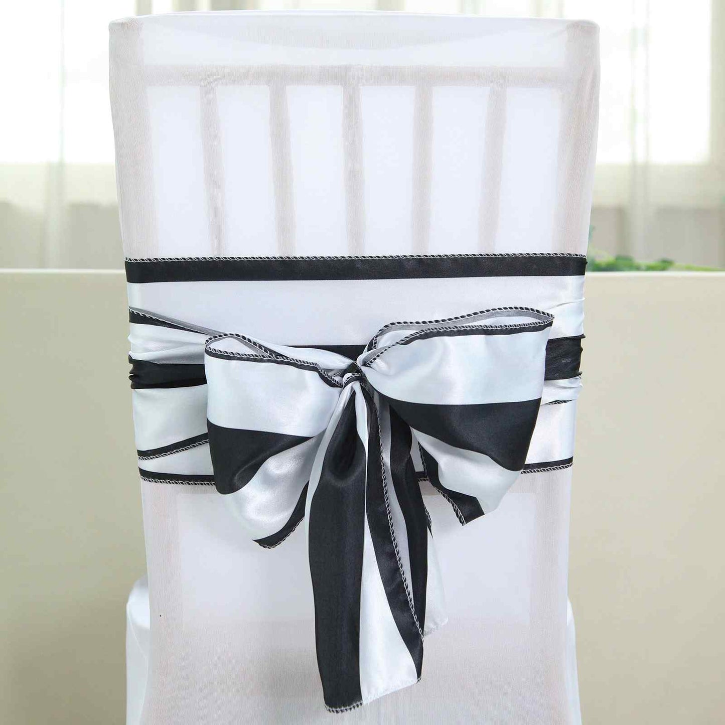 Black and white stripe satin chair sash on a white chair.