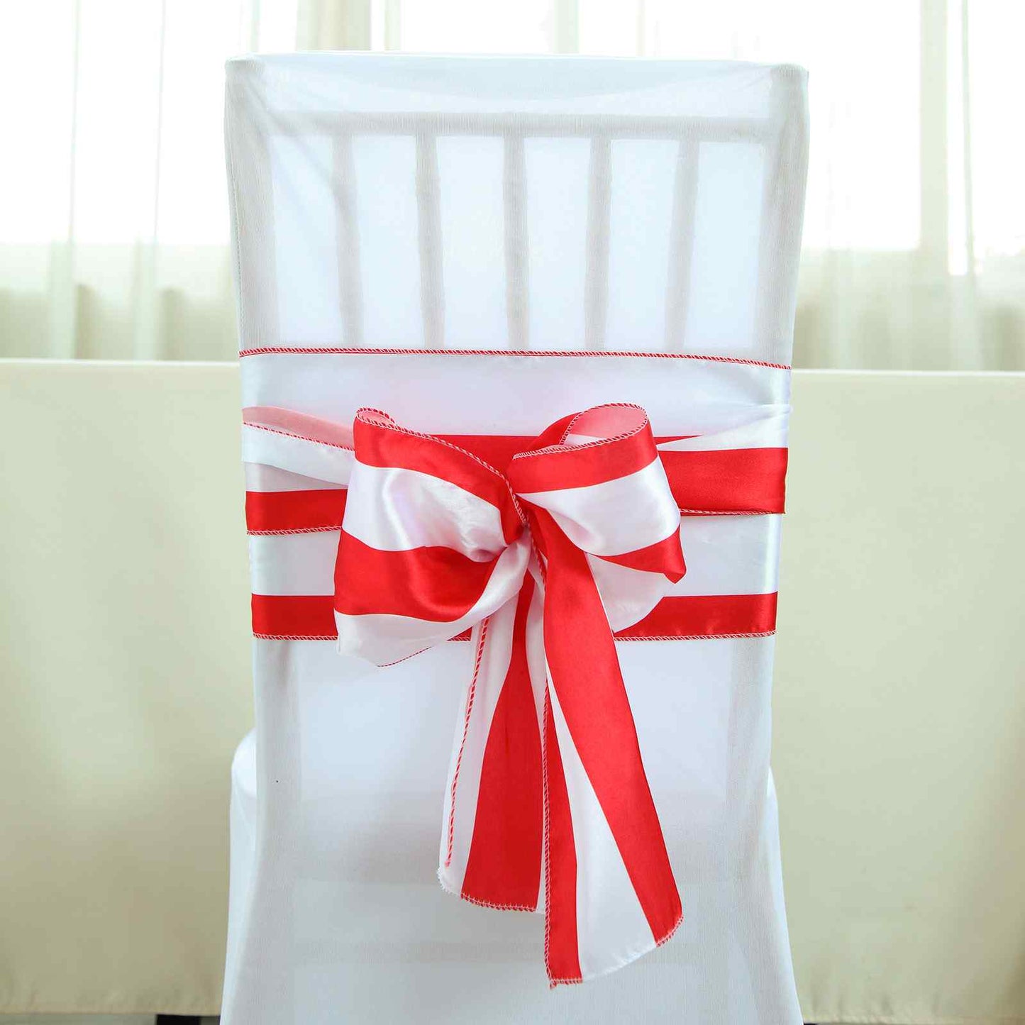 Red and white stripe satin chair sash on a white chair.