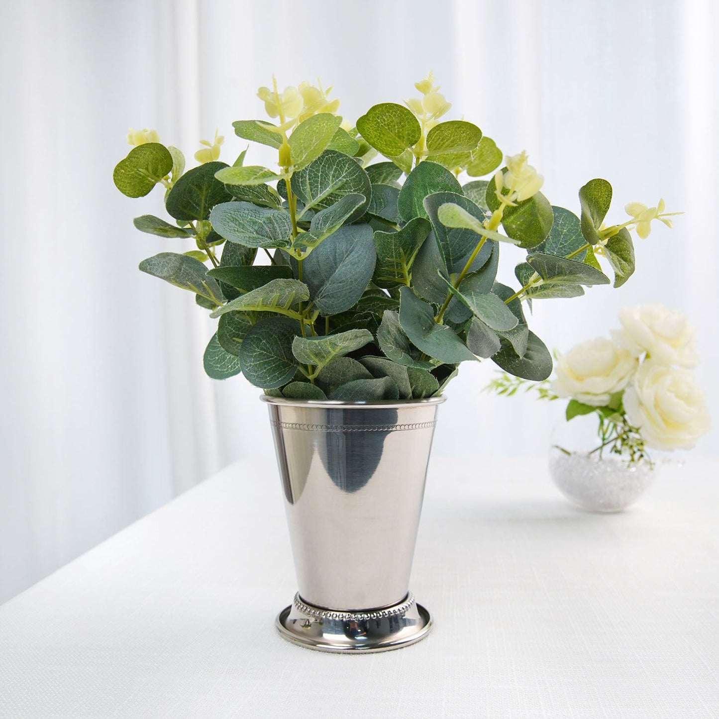 Silver mint julep cup vase with greenery and flowers.