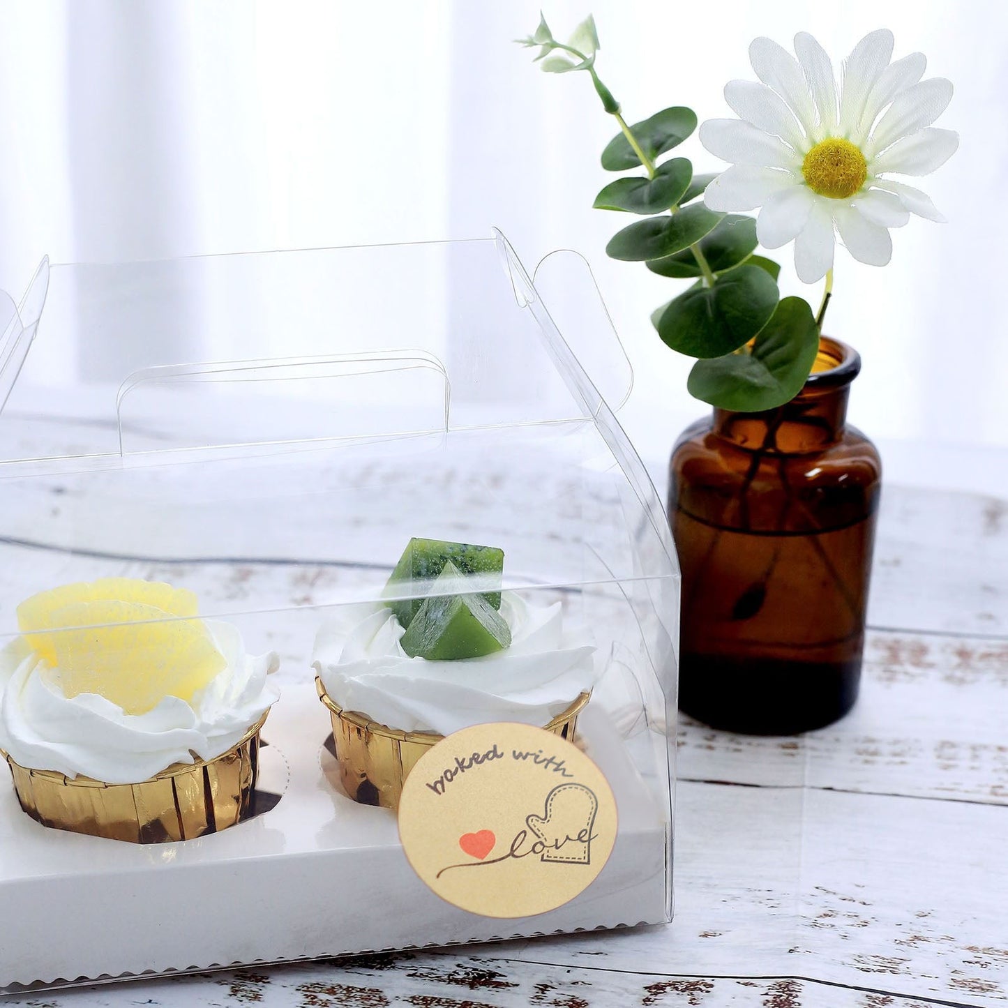 Baked with love stickers on bakery box with yellow and green cupcakes.