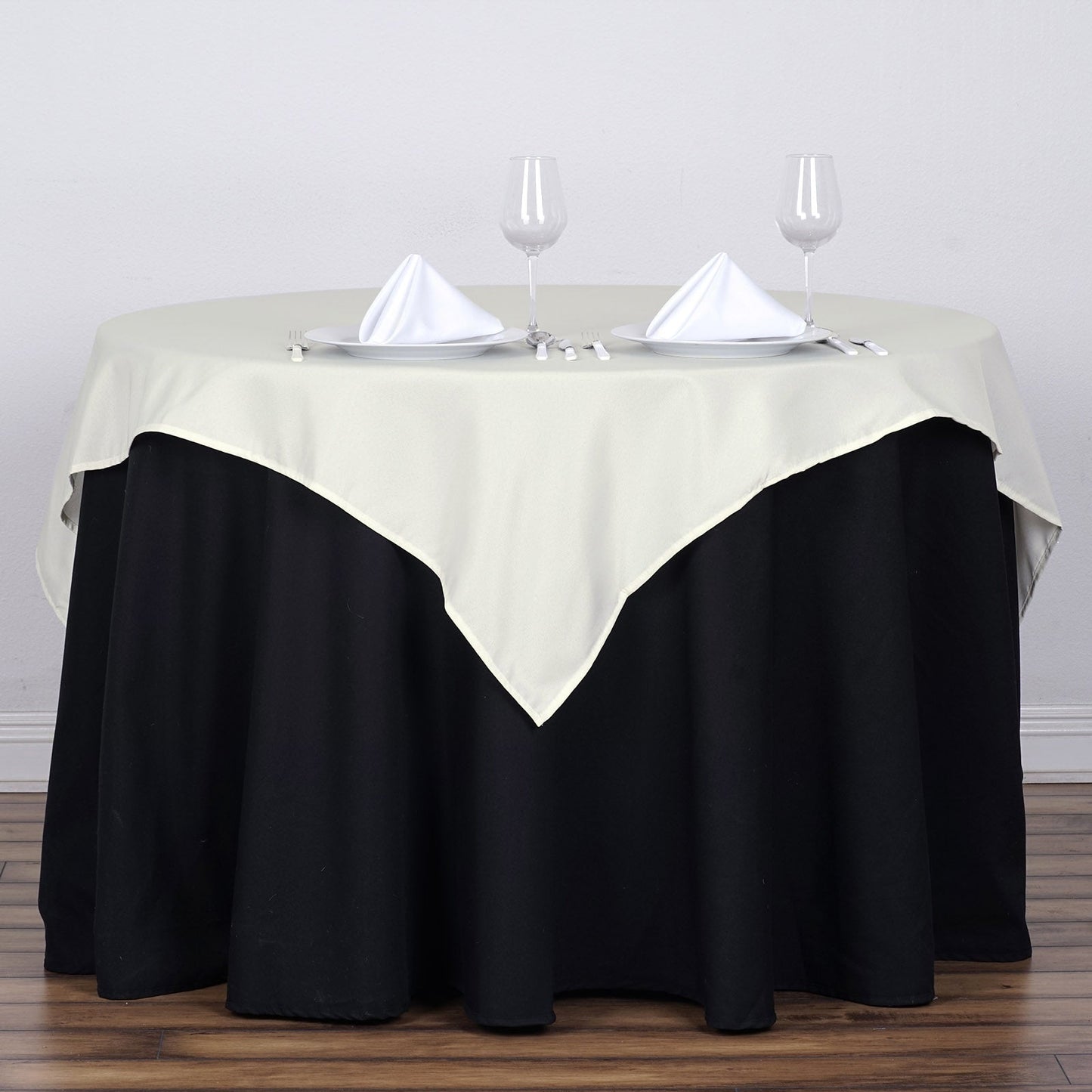 Ivory square tablecloth on a round table set for dining.
