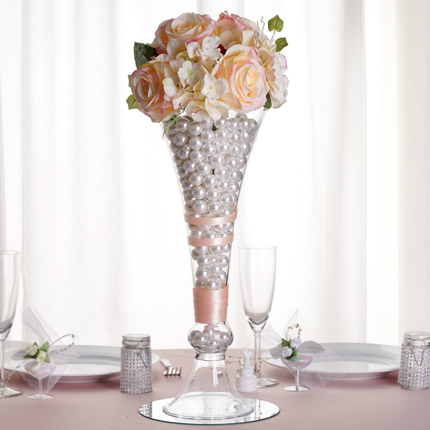 Clear trumpet glass vase with floral arrangement and decorative pearls.