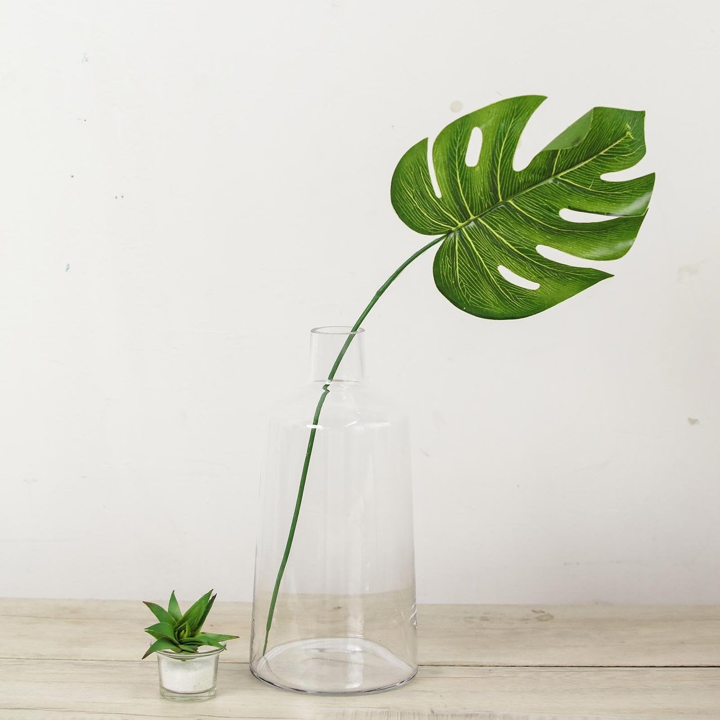 Clear glass flower bud vase with green leaf centerpiece.