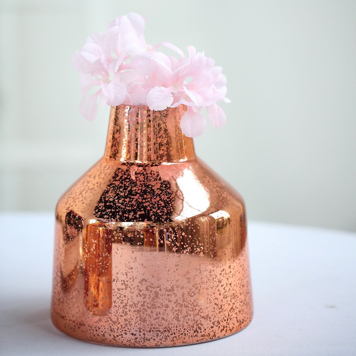 Rose gold mercury glass vase with pink flowers.