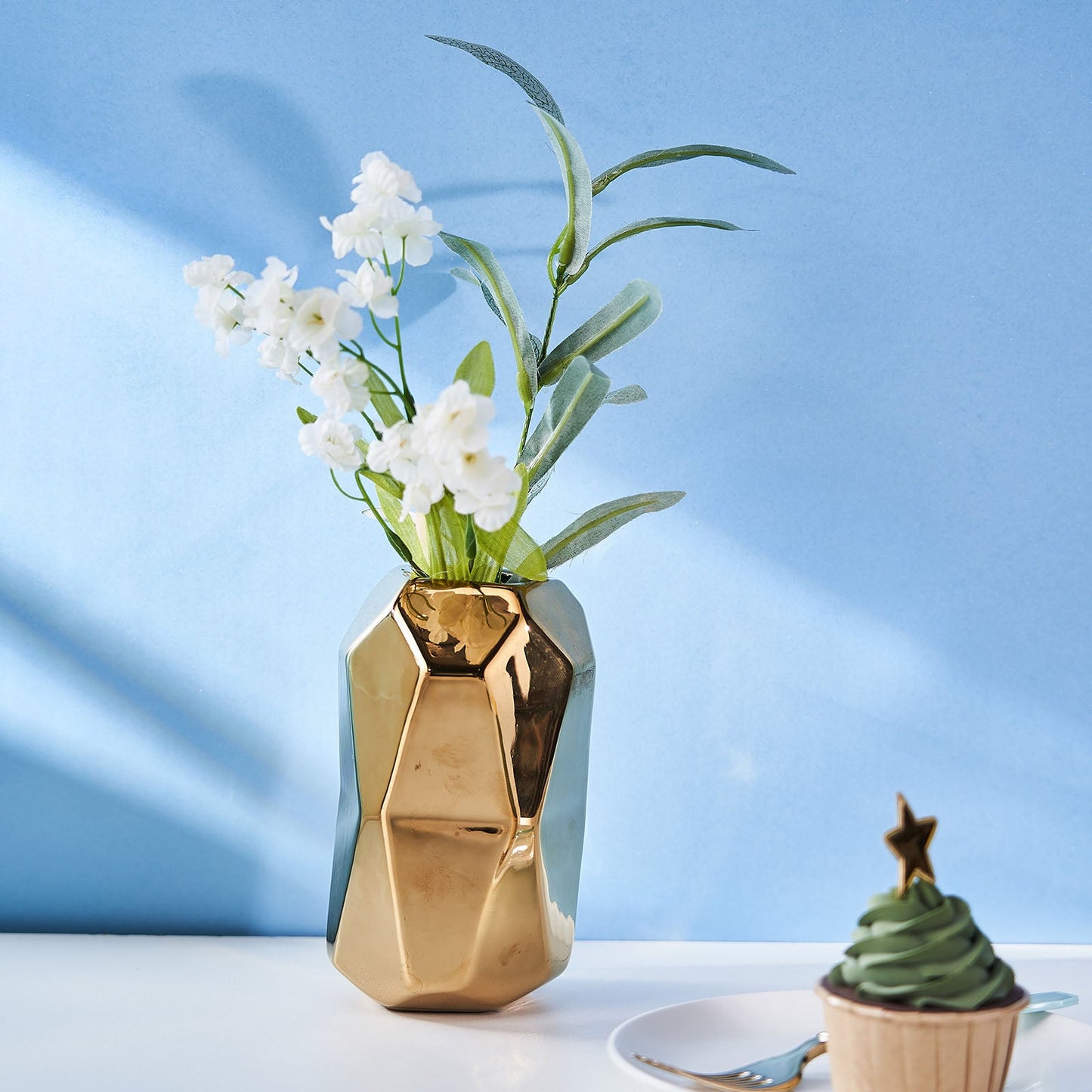 Gold metallic geometric ceramic vase with flowers.