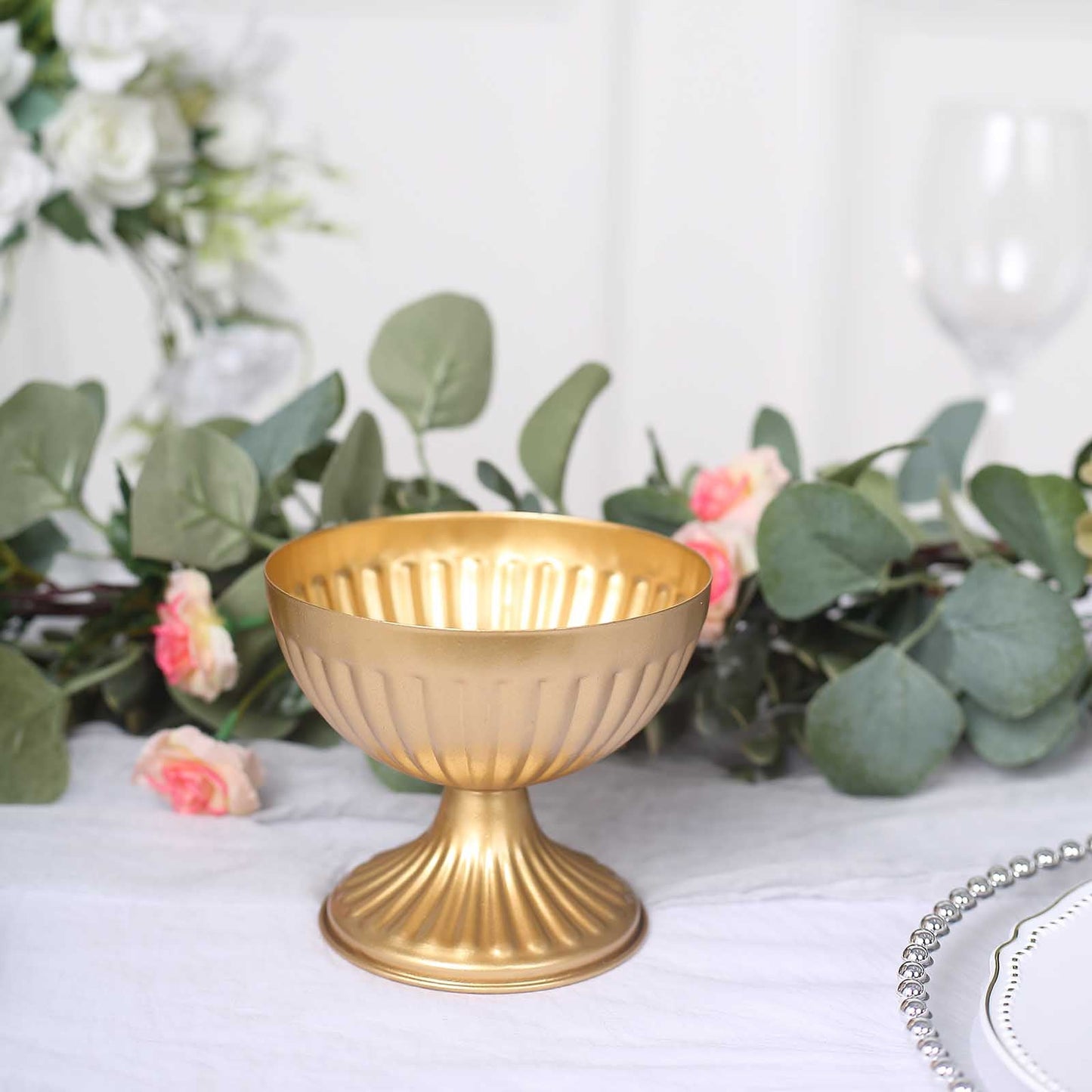Gold metal ribbed pedestal vase in antique style, perfect for floral arrangements.