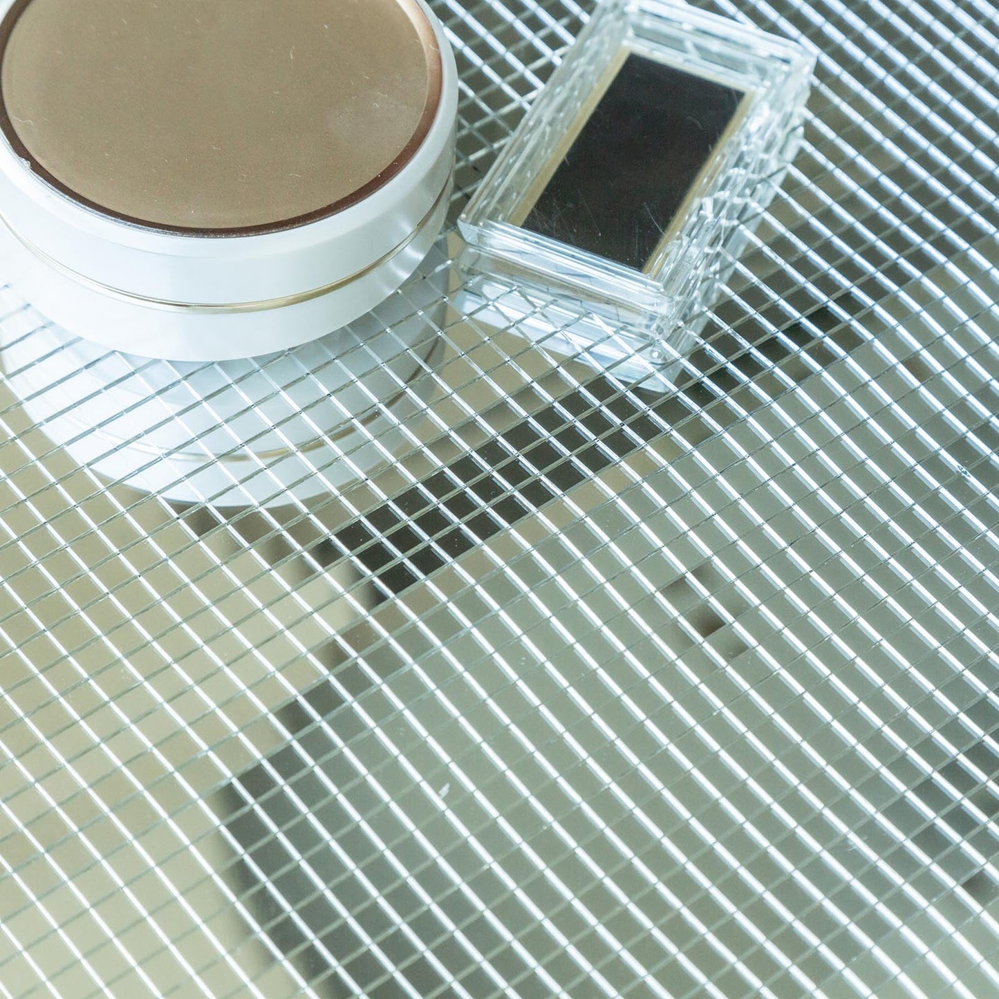 Silver peel and stick mosaic mirror wall tiles on a reflective surface.