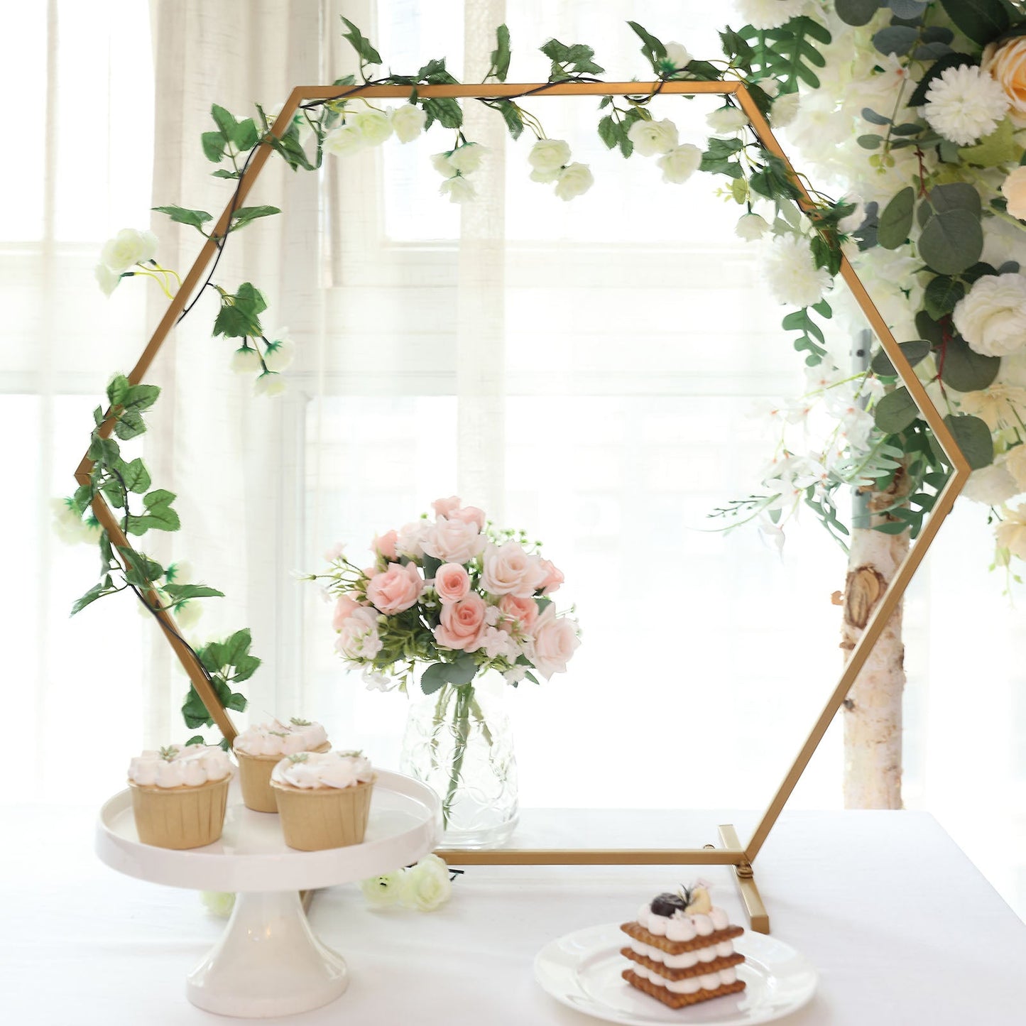 Gold hexagon table wedding arch centerpiece with flowers and treats.