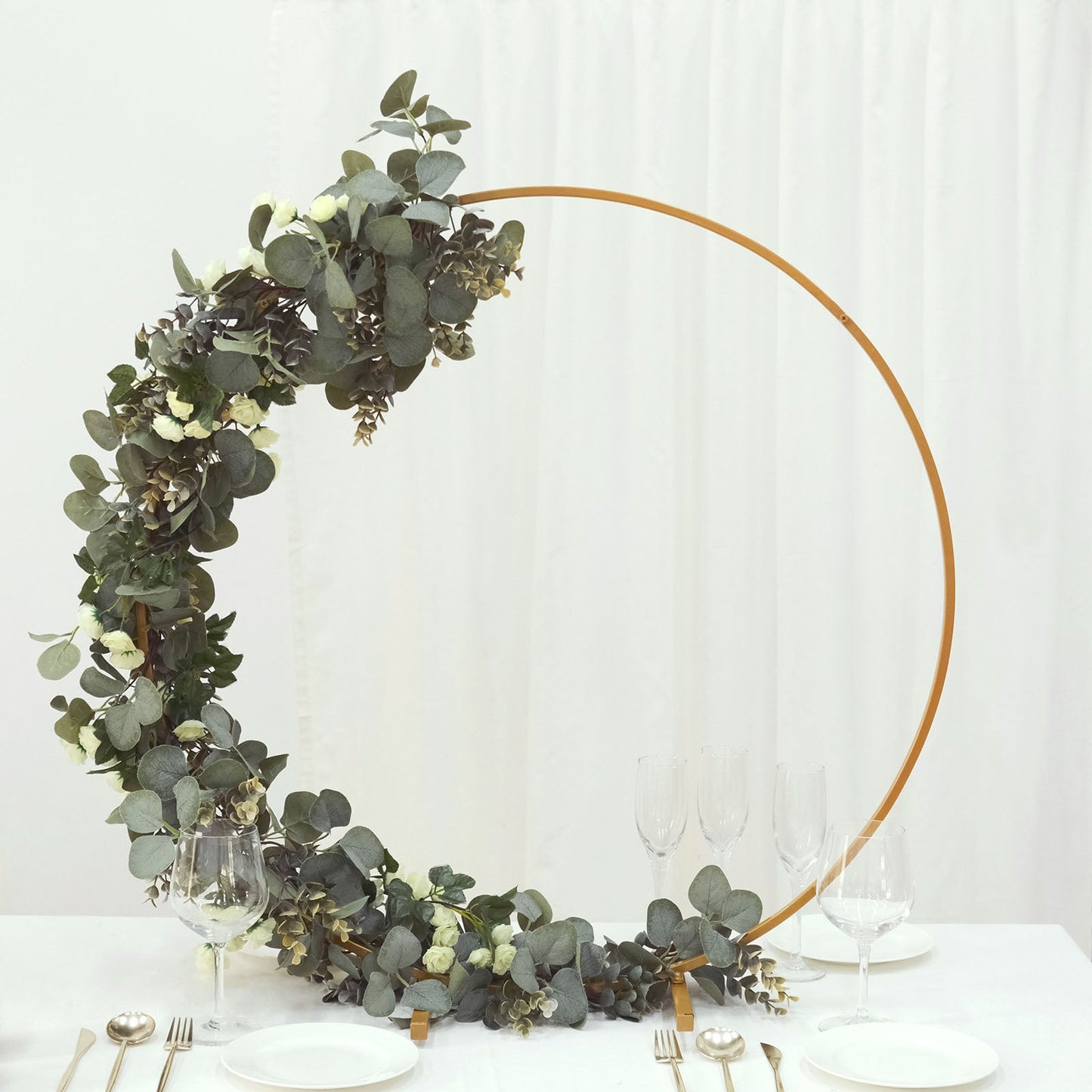 Gold metal round hoop floral centerpiece with greenery.
