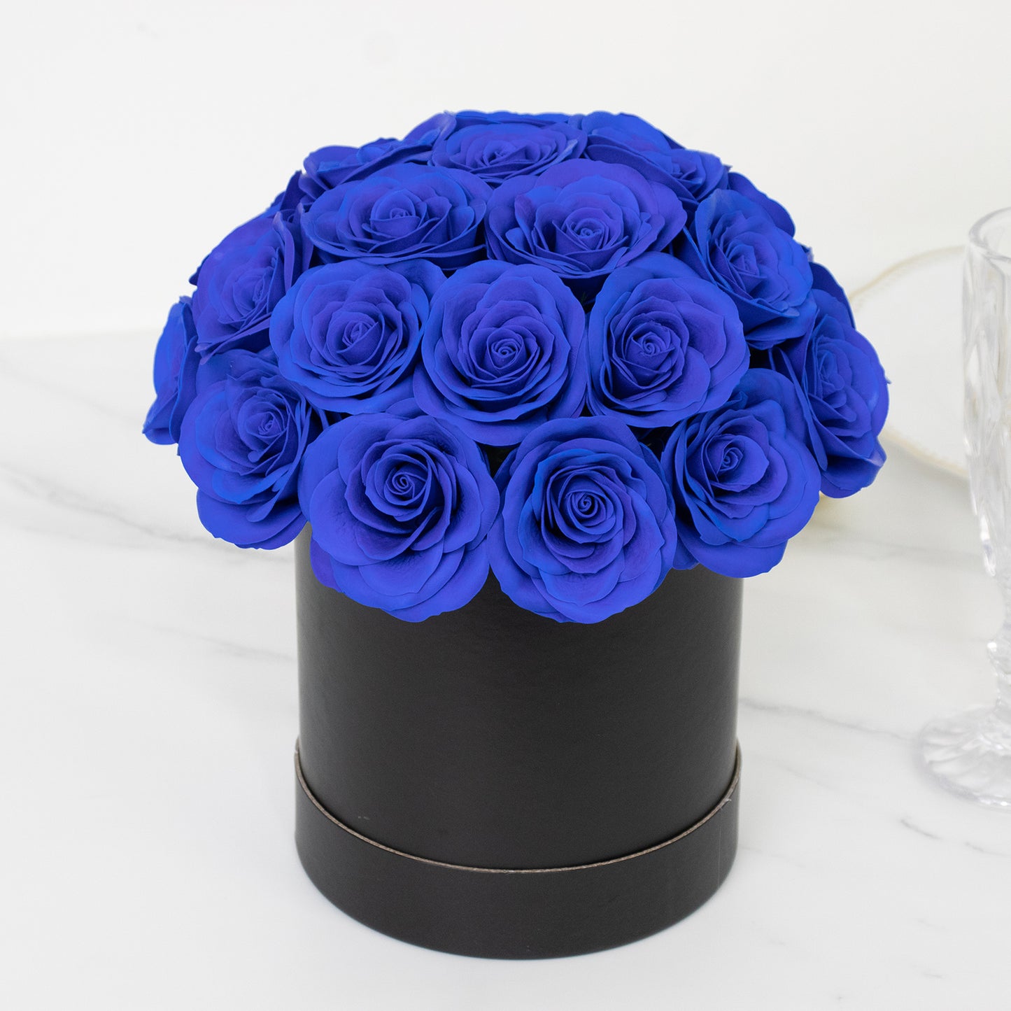 Royal blue rose centerpiece arrangement in a black round gift box.
