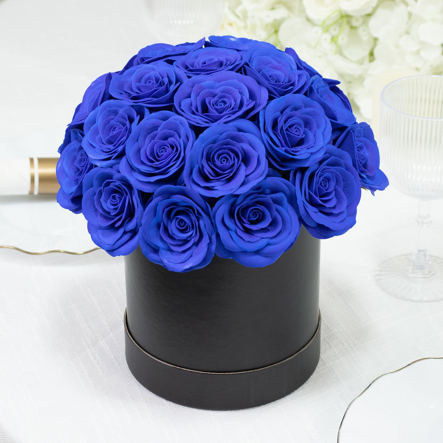 Royal blue rose centerpiece arrangement in a black round gift box.