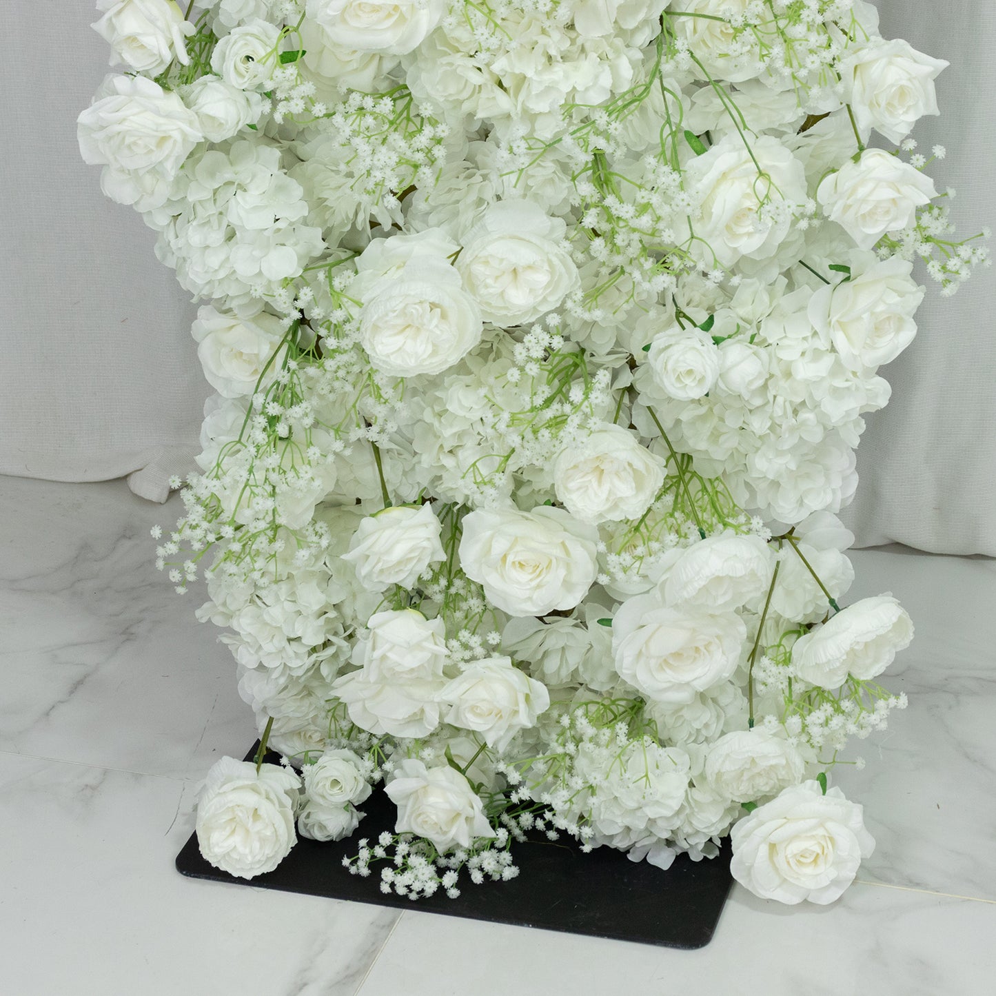 White artificial flower backdrop with silk roses and baby's breath.