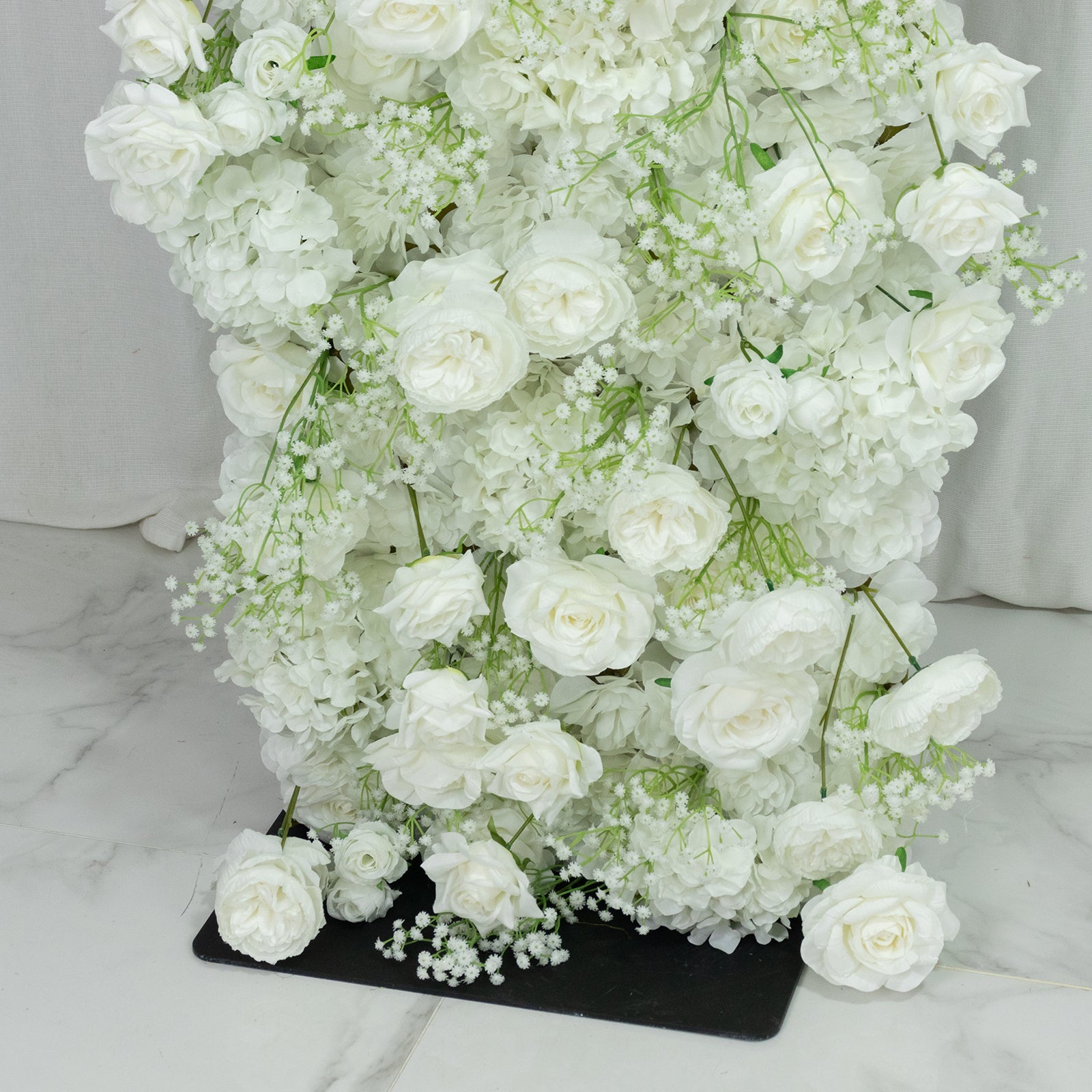 White artificial flower backdrop with silk roses and baby's breath.