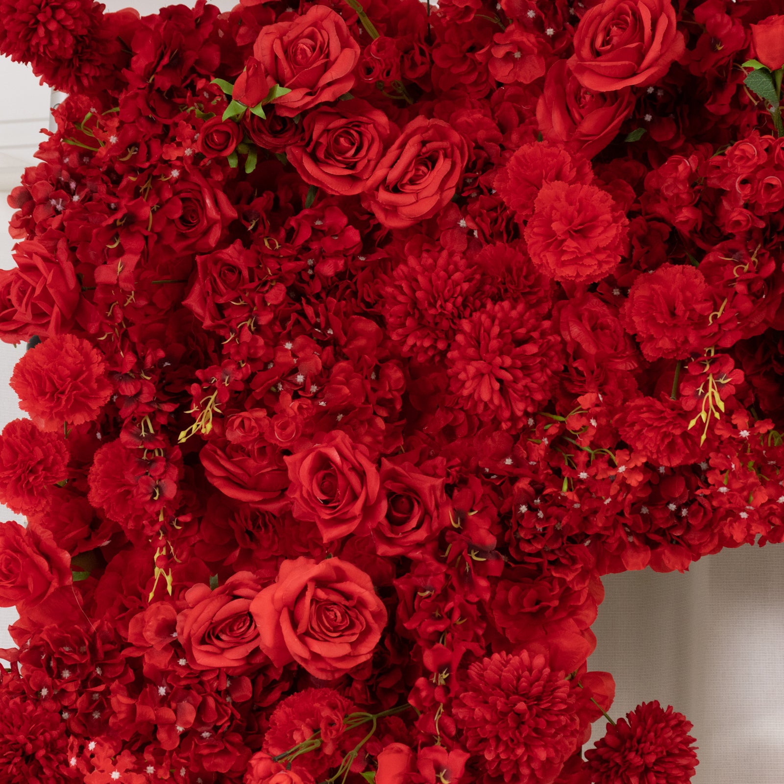 Red floral backdrop with artificial silk roses, hydrangeas, and chrysanthemums.