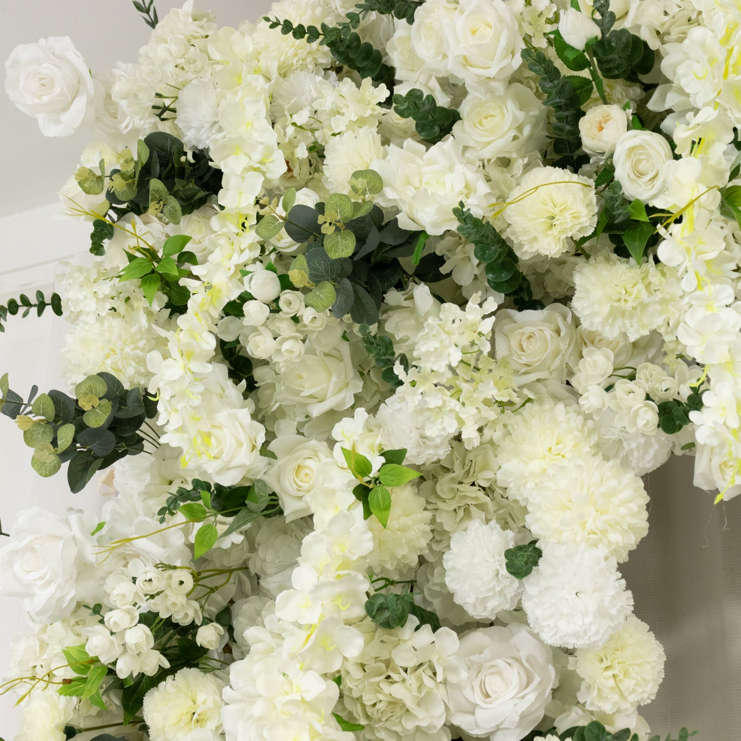 White artificial flower backdrop with silk roses and hydrangeas for weddings.