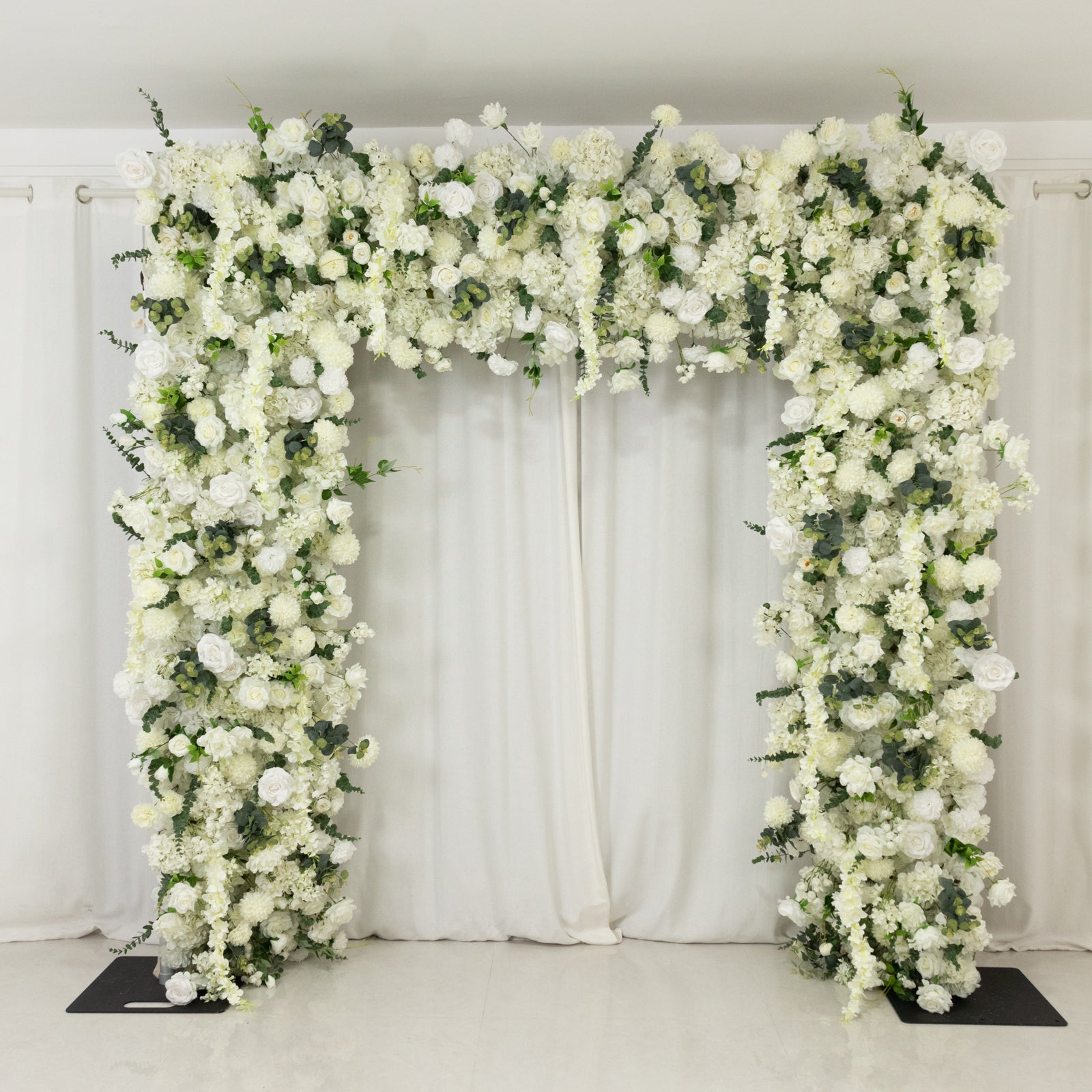 White roll-up flower backdrop with artificial silk roses, hydrangeas, and chrysanthemums.