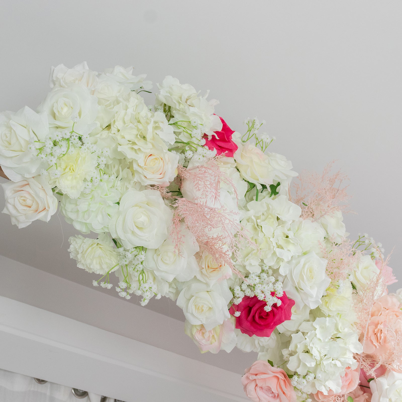 White and pink floral backdrop for wedding arch with roses and hydrangeas.