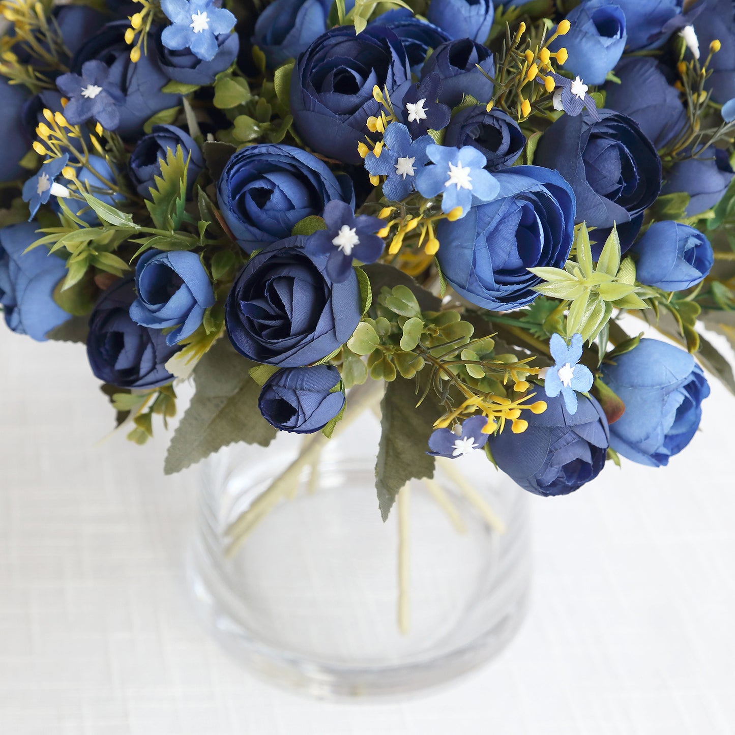 Navy blue artificial ranunculus bouquet in a glass vase.
