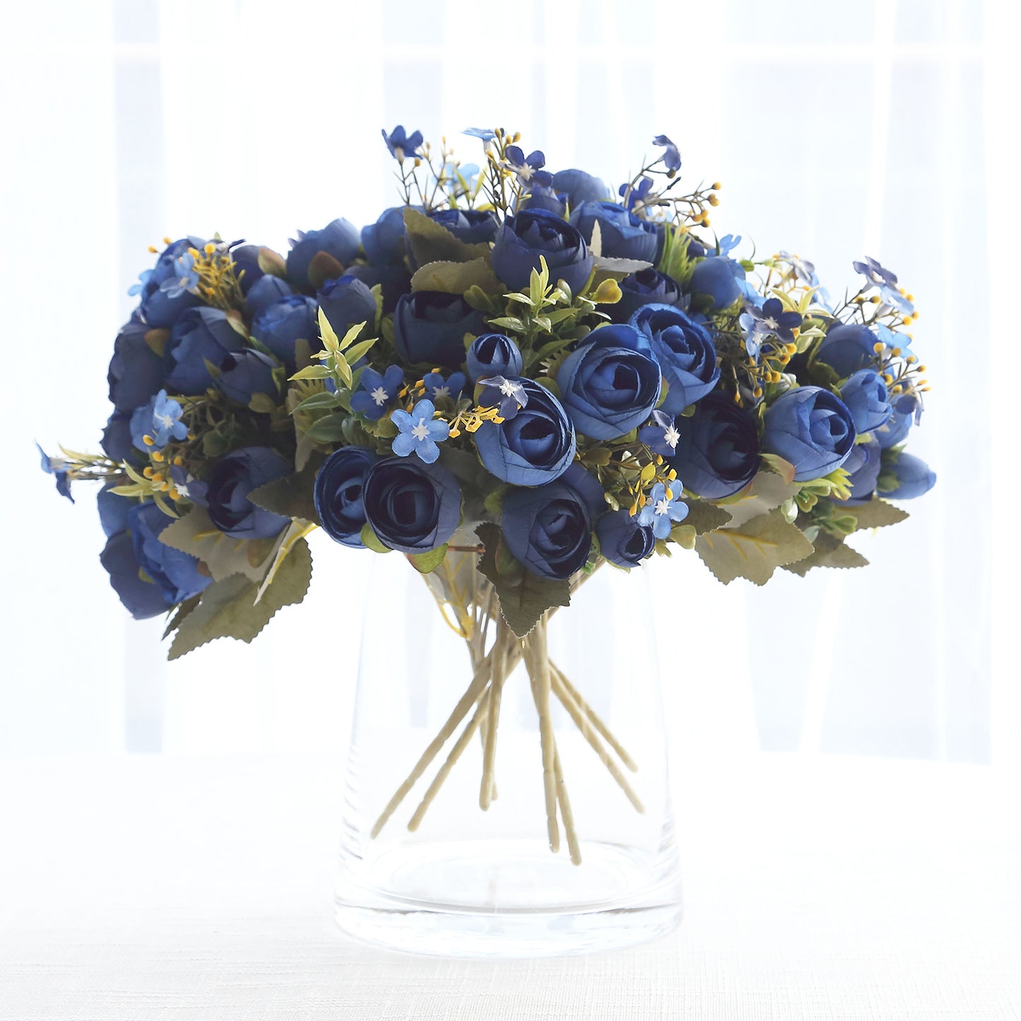 Navy blue artificial ranunculus flower bouquet in a clear vase.