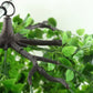 Green artificial eucalyptus leaf vines hanging from a chandelier.